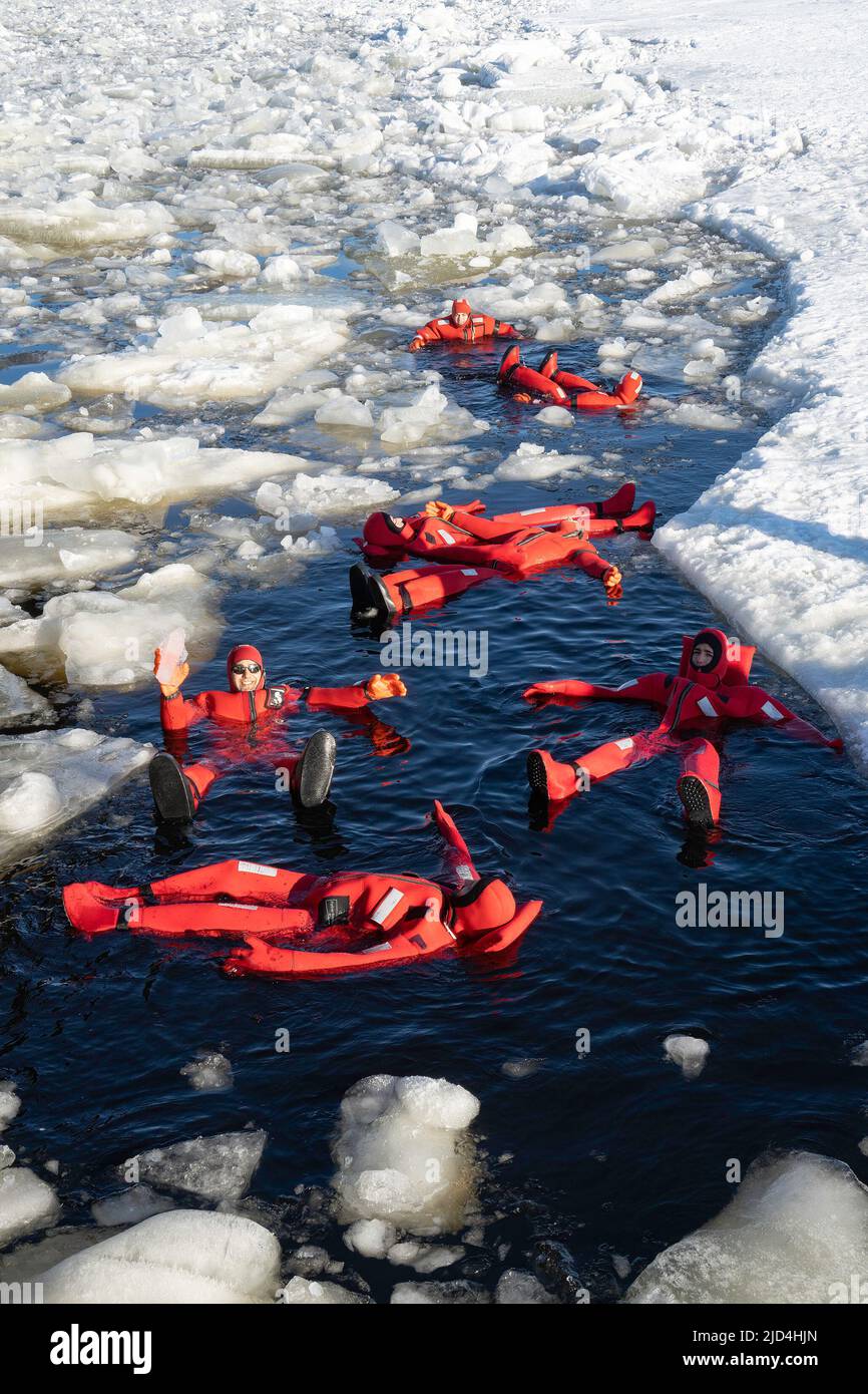 Rovaniemi, Finnland - 21.. März 2022: Eine Gruppe von Touristen schwimmt im gefrorenen Wasser der auftauenden ostsee mit Isolieranzügen. Stockfoto