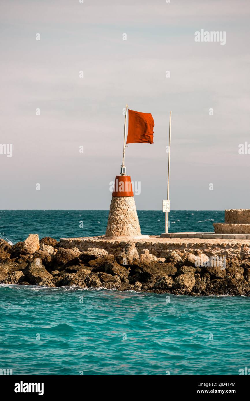 Rote Flagge auf einem Posten in der Nähe einer türkisblauen Hafenmarina in Hurghada Ägypten, um Boote zu warnen Stockfoto