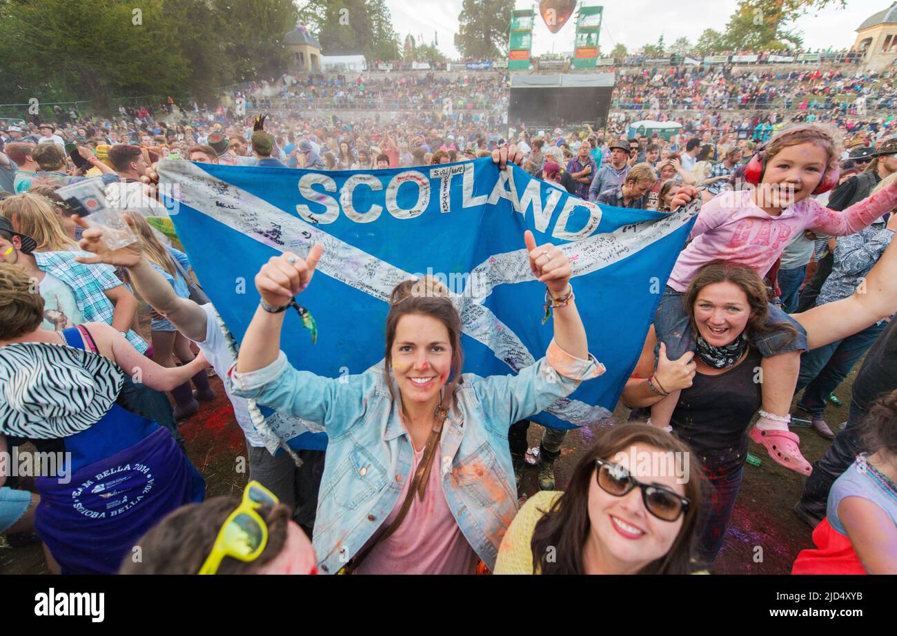 Festivalbesucher werfen auf der Hauptbühne des Belladrum Tartan Hearts Festivals in Inverness, Großbritannien, buntes Pulver Stockfoto