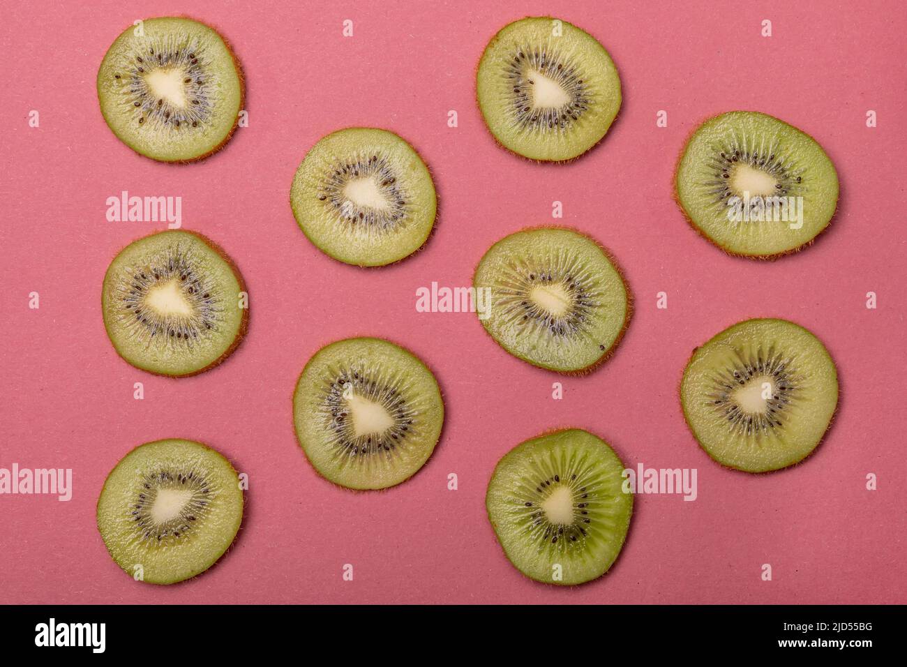 Draufsicht auf Kiwi-Scheiben auf rotem Hintergrund Stockfoto