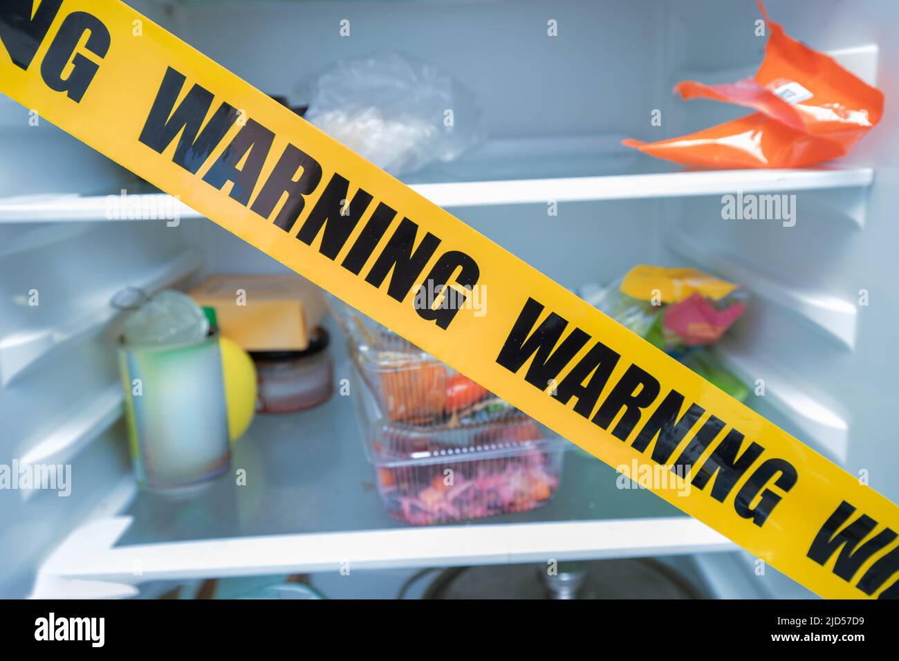 Kühlschrank mit Schutzband mit der Aufschrift Warnung geschlossen. Das Konzept von Hunger und Überernährung oder pathogenen Mikroben und verdorbenen Lebensmitteln Stockfoto