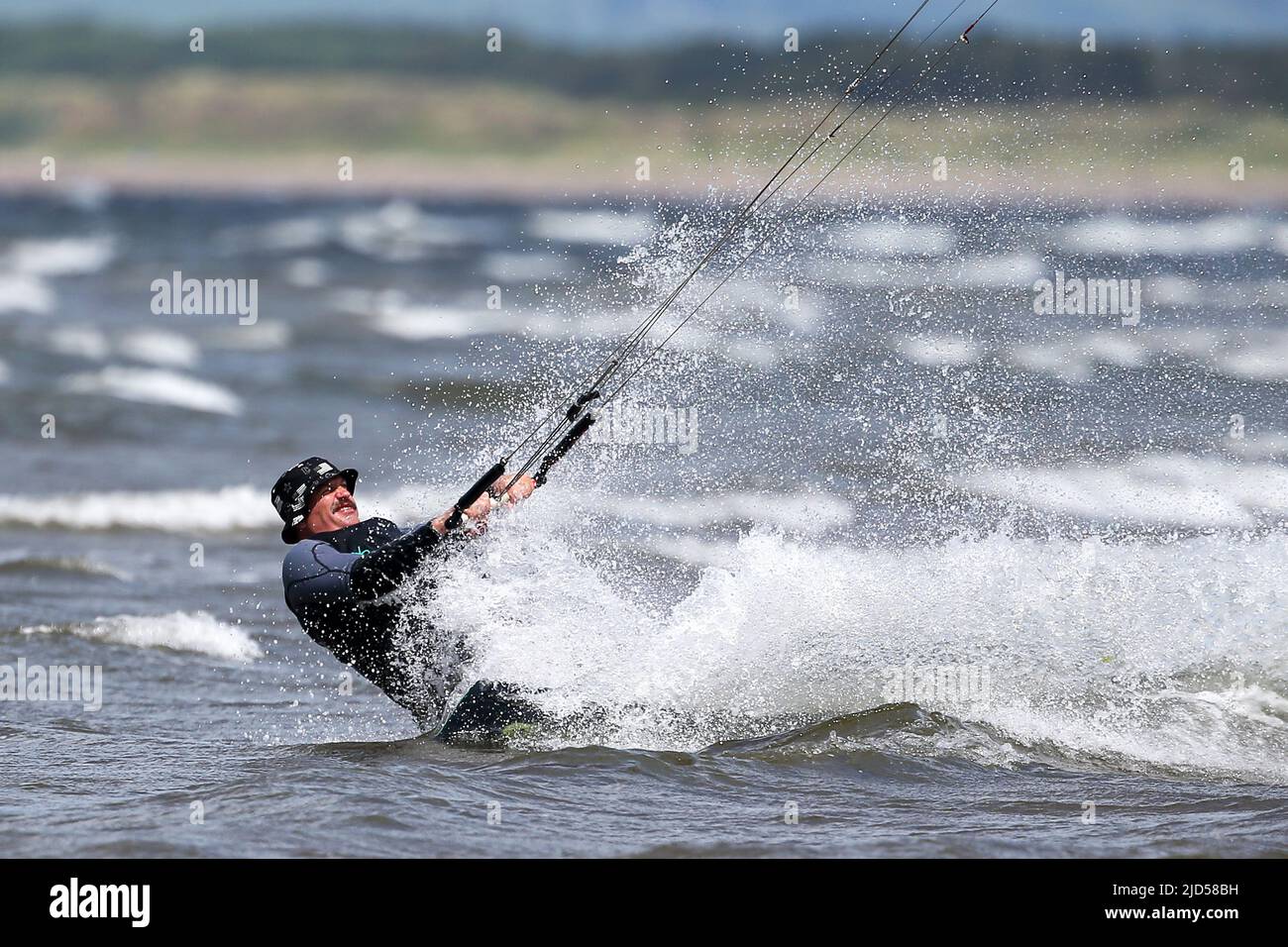 Troon, Großbritannien. 18.. Juni 2022. Starke Winde, hohe Wellen und Sonnenschein sorgten für ideale Bedingungen für die Kitesurfer und Wassersportler, die das Sommerwetter am Firth of Clyde, vor South Beach, Troon, Schottland, Großbritannien, nutzen. Kredit: Findlay/Alamy Live Nachrichten Stockfoto