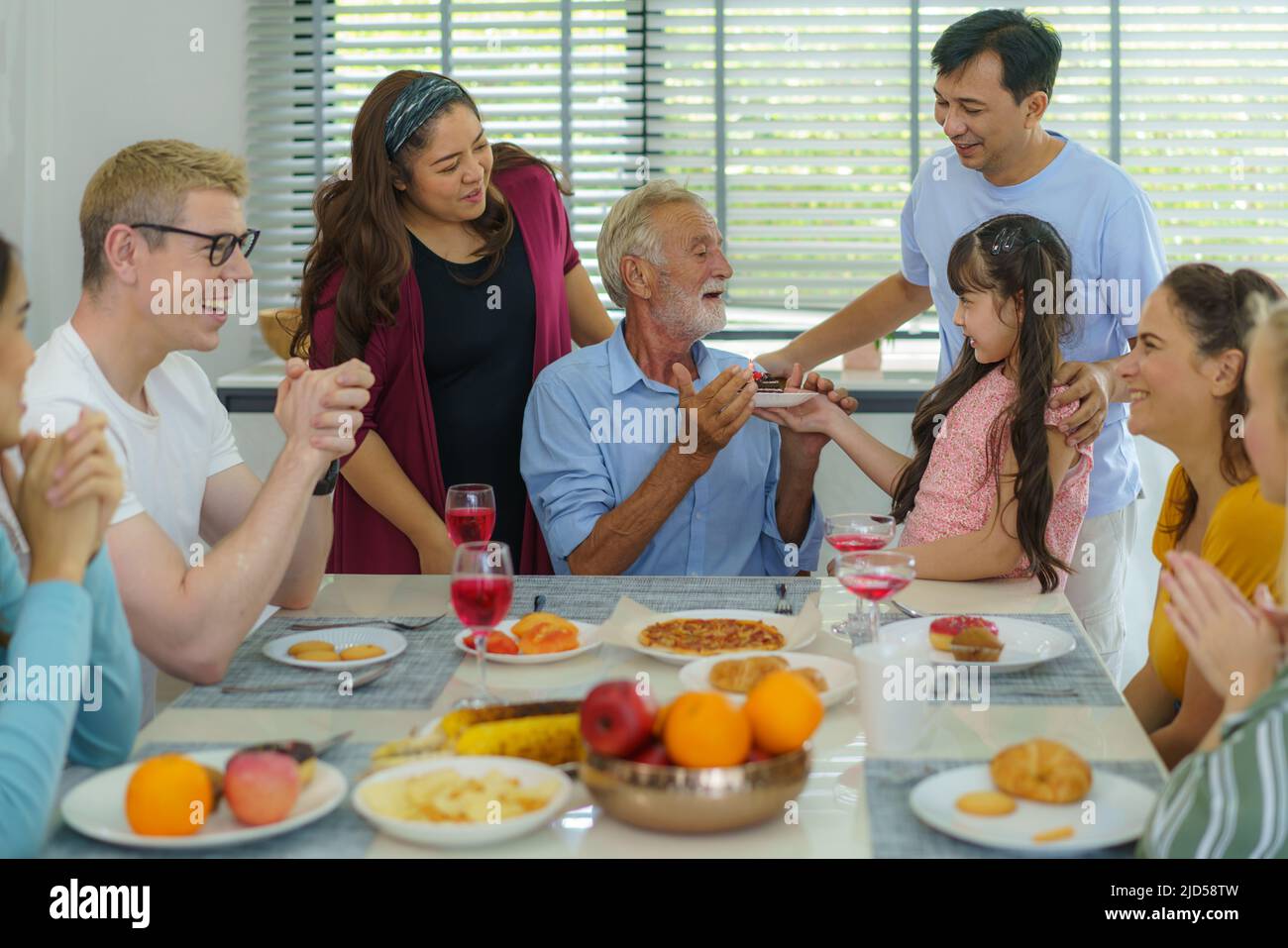 Glückliche Mutiethnizität und Mehrgenerationenfamilie feiern Großväter Geburtstag im Wohnzimmer zu Hause. Stockfoto