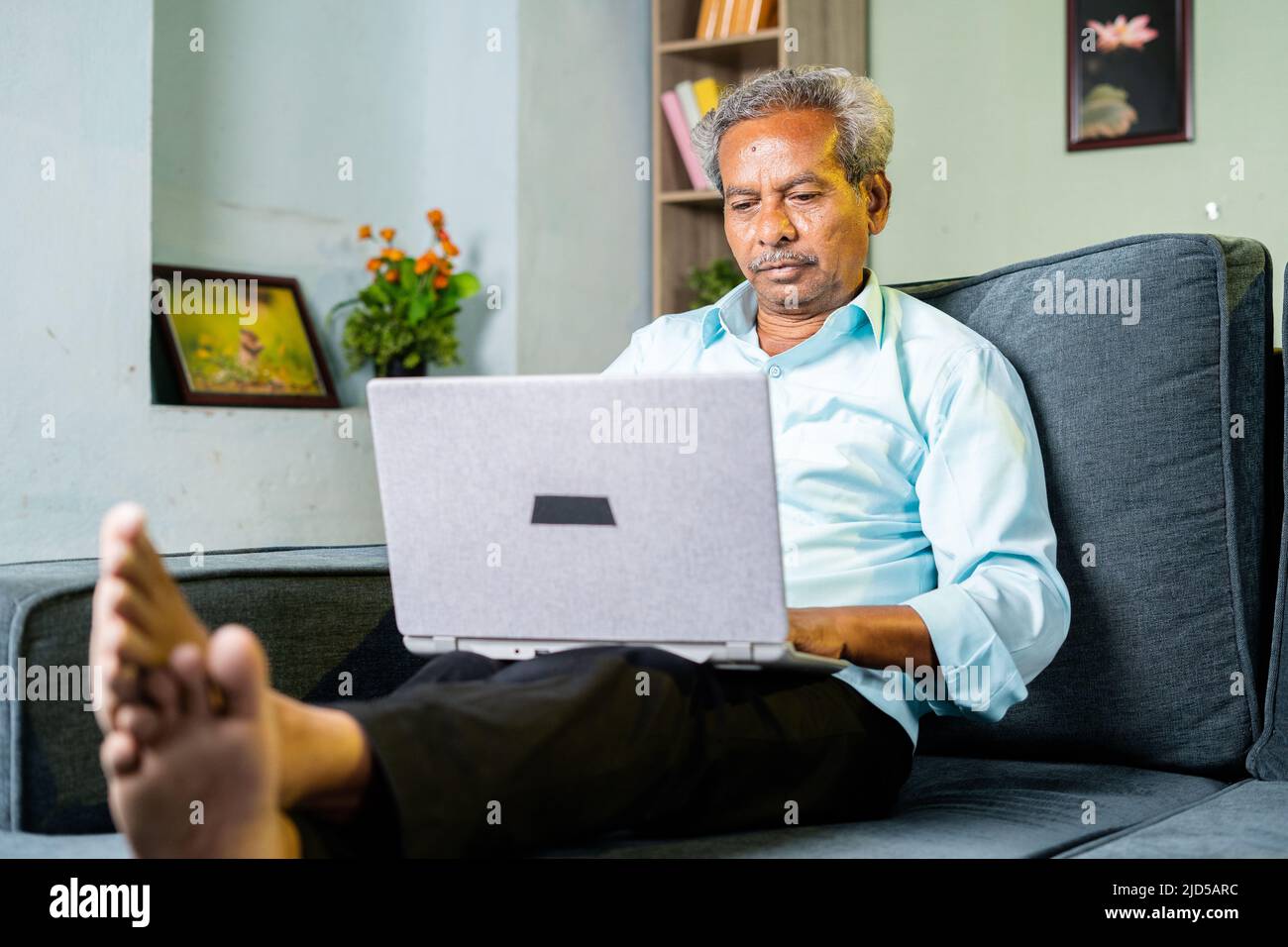 Senior alter Geschäftsmann beschäftigt mit Laptop zu Hause auf dem Sofa - Konzept der Cyberspace, Konzentration und Altersvorsorge Stockfoto