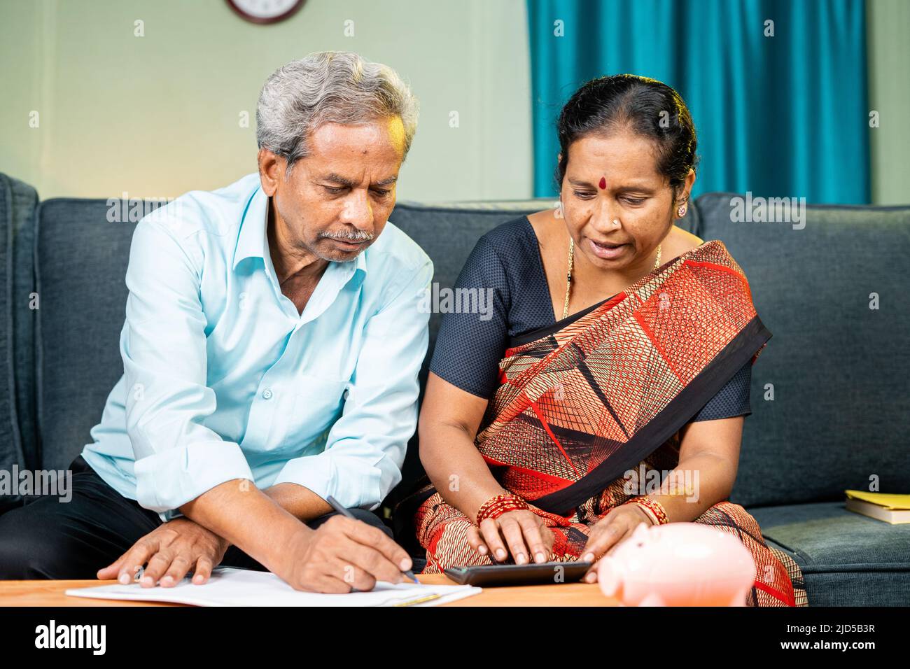 Das ältere Paar ist damit beschäftigt, das Budget und die Ausgaben der Rechnungen zu Hause auf dem Sofa zu berechnen - ein Koncpet aus Geldmanagement, Finanzen und Banken Stockfoto