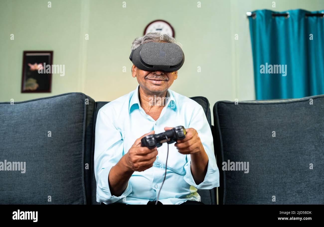Happy Smiling Alter Mann erleben VR-Headset durch Videospiel mit Gamepad zu Hause spielen, während auf dem Sofa sitzen - Konzept der Technologie und Stockfoto