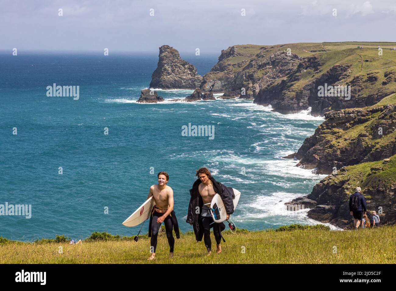 Zwei junge Surfer mit Boards freuen sich nach einem Tag auf den atemberaubenden Küstenwellen in der Nähe von Tintagel Cornwall England Stockfoto