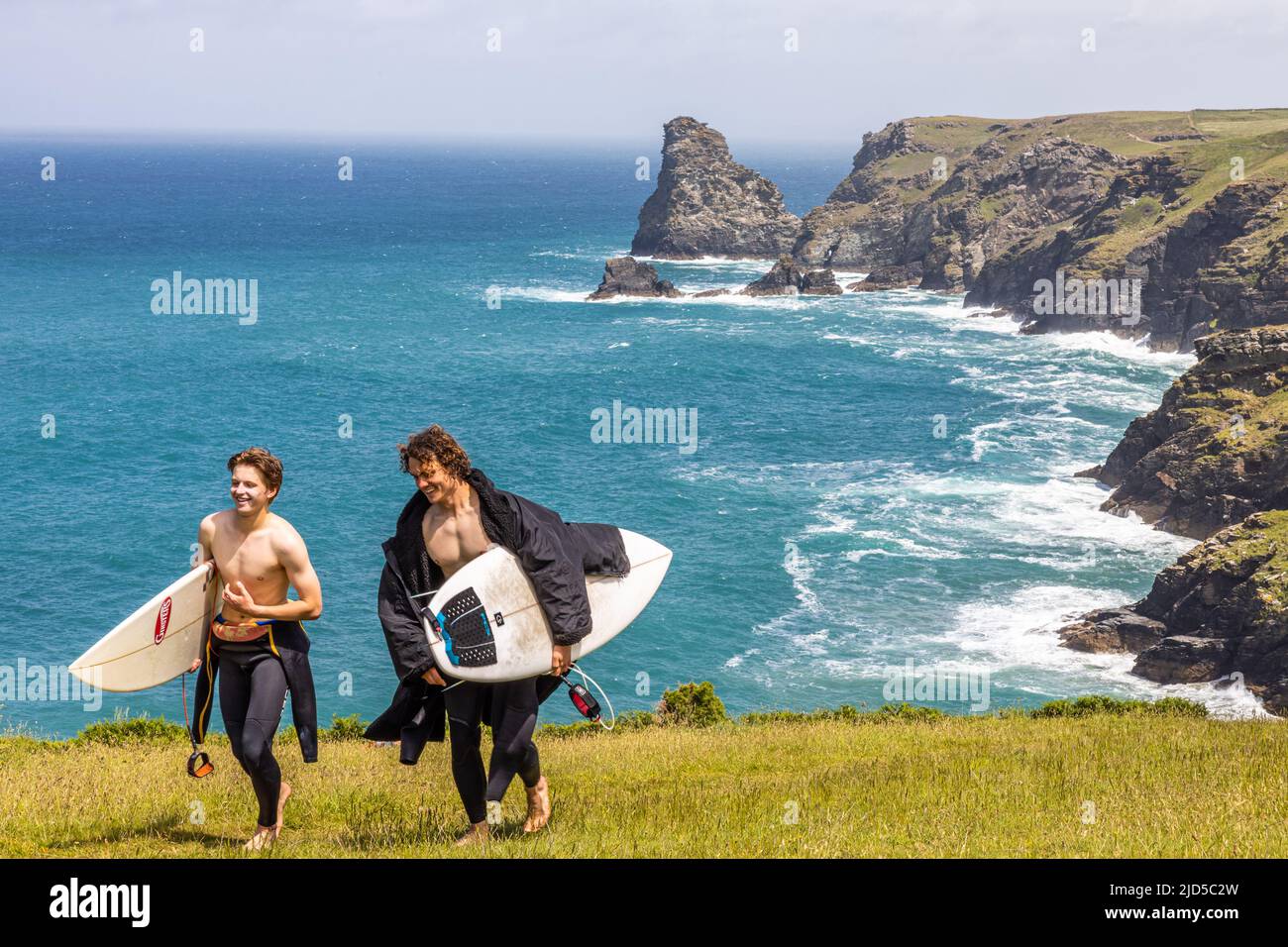 Zwei junge Surfer mit Boards freuen sich nach einem Tag auf den atemberaubenden Wellen in der Nähe von Tintagel Cornwall England Stockfoto