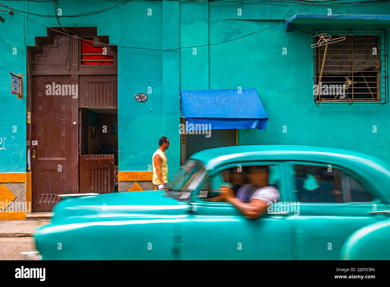 Grün-blauer Oldtimer passiert ein Haus in der gleichen Farbe in Alt-Havanna, Kuba Stockfoto