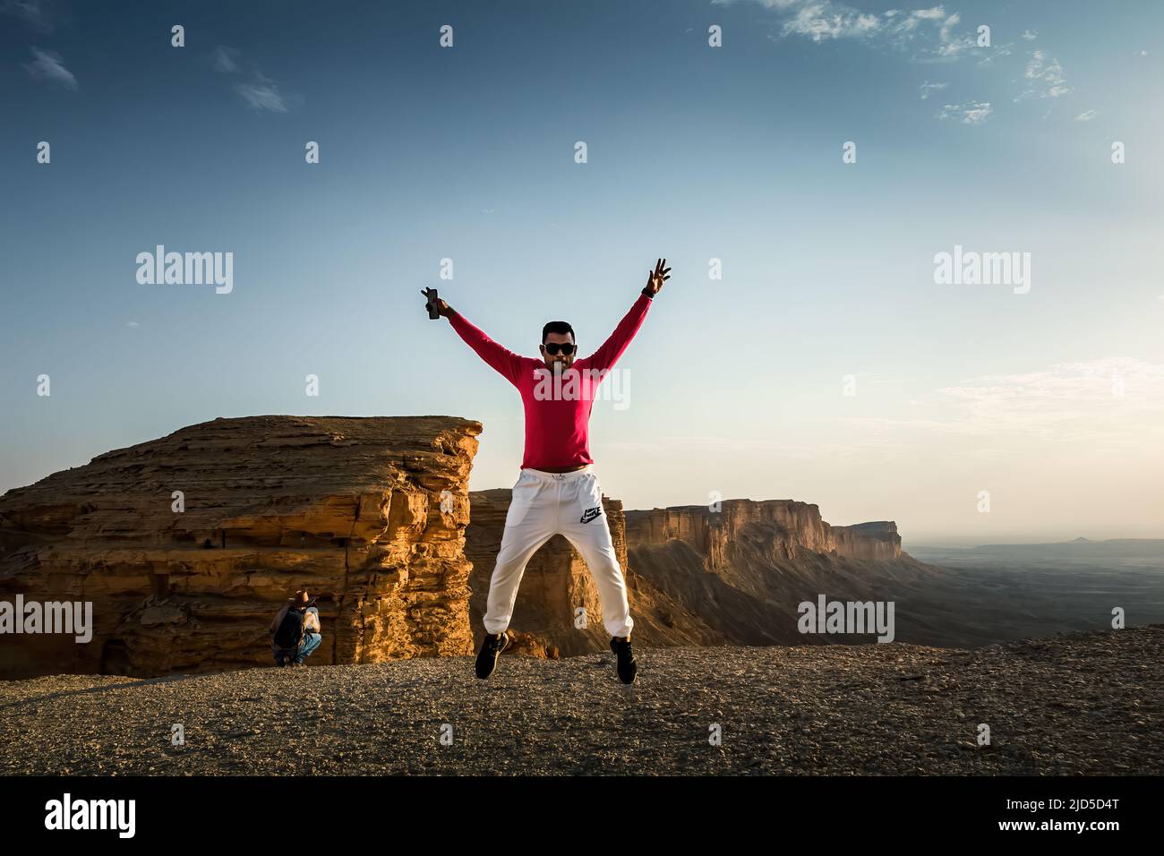 Happy man springende Silhoutte Posen mit schönen Sonnenuntergang Hintergrund in Edge of the world Riad Saudi-Arabien. Stockfoto
