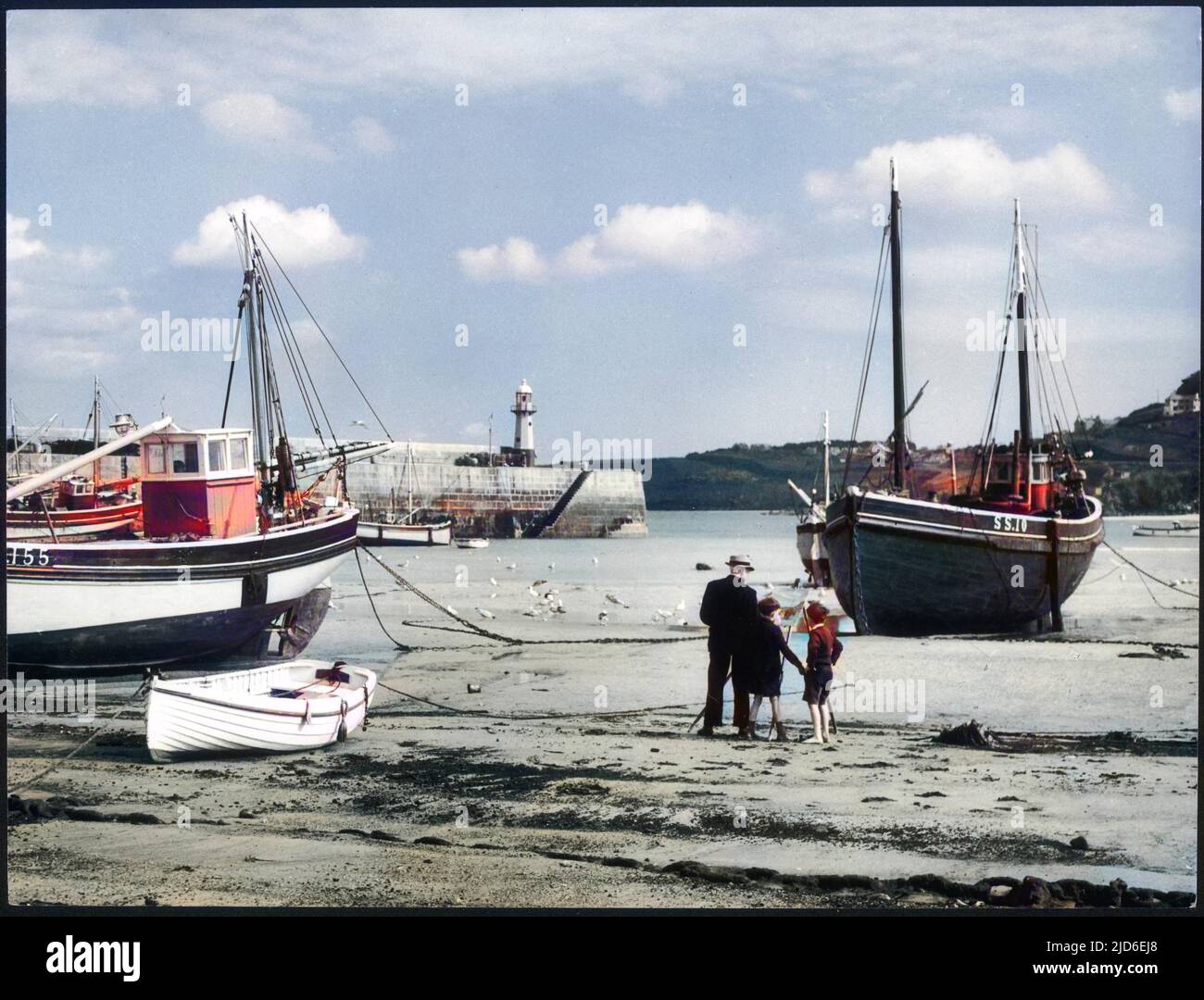 Zwei kleine Jungen halten ihren Großvater in Begleitung, während er sein Gemälde eines Fischtrawlers am Strand in der Nähe des Hafens von St. Ives, Cornwall, beendet. Kolorierte Version von : 10146302 Datum: 1950s Stockfoto