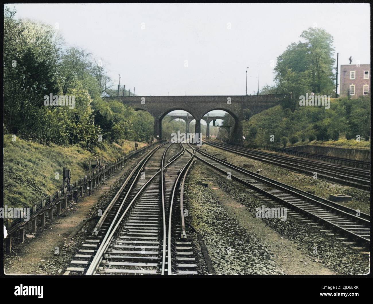 Der Blick aus dem Fahrerhaus auf einen elektrischen Hauptzug, der die Surbiton Station, Surrey, England, verlässt und die Strecke und die Brücke vor sich zeigt. Kolorierte Version von : 10156218 Datum: 1940s Stockfoto