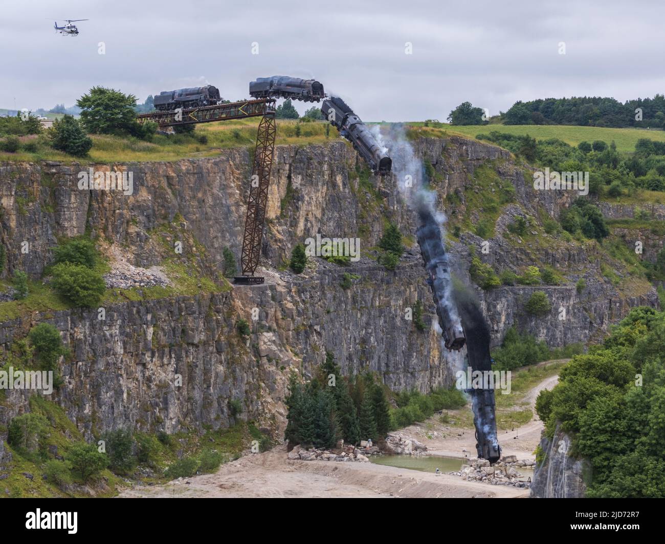***Video verfügbar*** Mission: Impossible 7 Lokomotivzug-Crashszene in Stoney Middleton, Derbyshire. Der nachgebaute Dampfzug der British Railway Britannia wird für die letzte Crashszene in Tom Cruise's neuestem Blockbuster-Film von der Klippe getrieben. Die Lokomotive fliegt in spektakulärem Stil durch die Luft, bevor sie in den Steinbruch darunter stürzt. Die Szene wurde von zwei Hubschraubern und vielen entfernten Kameras gefilmt. Tom Cruise kam kurz vor der letzten Absturzszene in seinem Personalhubschrauber an, er flog um den Film, bevor er auf den Feldern in der Nähe der Eisenbahnstrecke über dem Steinbruch landete. Der Dampfstoß tr Stockfoto