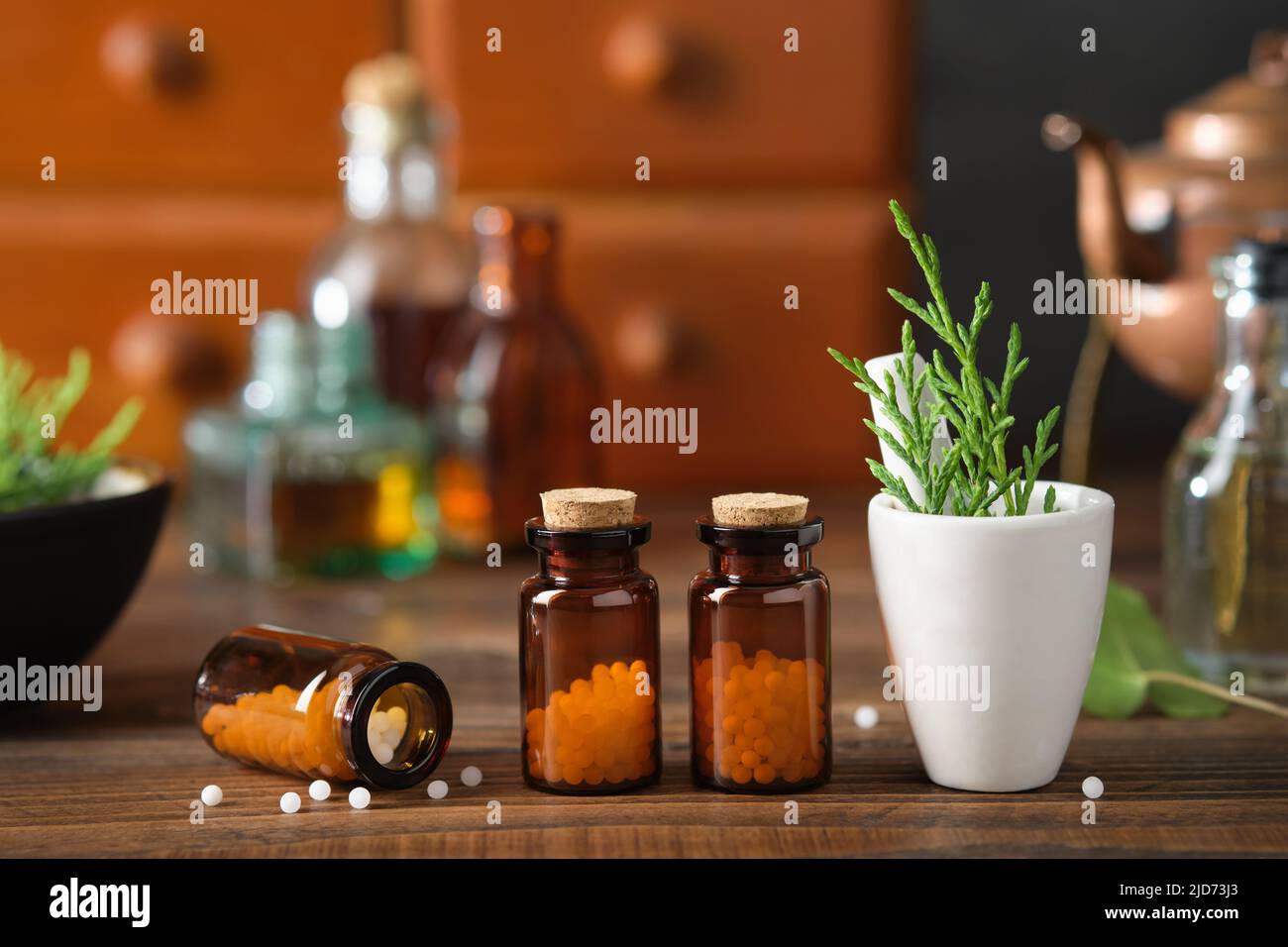 Flaschen mit homöopathischem Granulat, Schrank mit homöopathischen Mitteln und Tinktur-Flaschen auf dem Hintergrund. Konzept der Homöopathie. Stockfoto