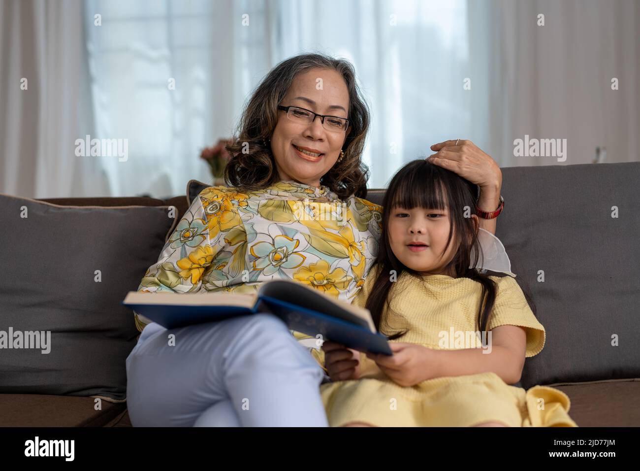 Glücklich asiatische Familie Großmutter Lesung zu Enkelin Buch zu Hause Stockfoto