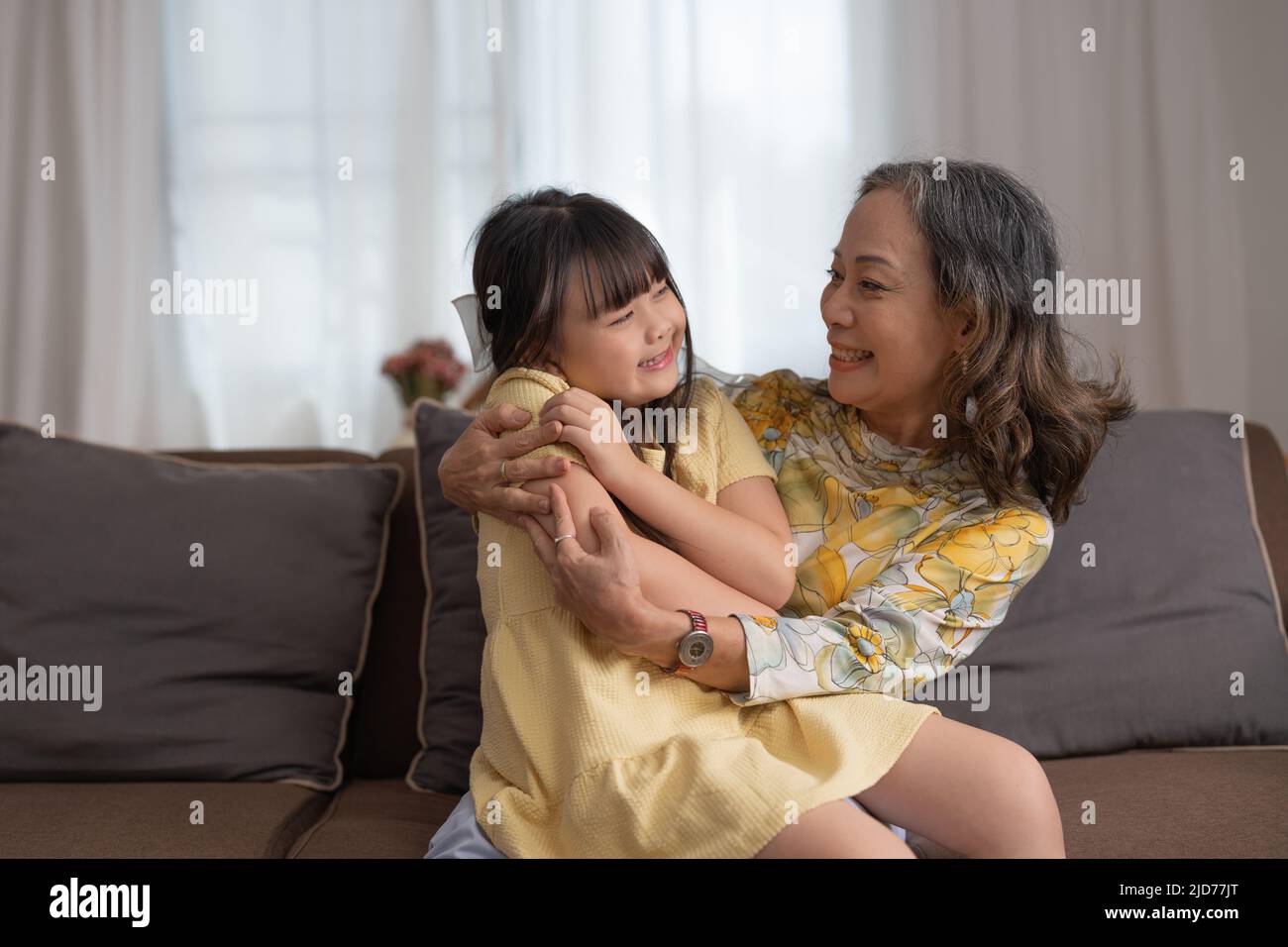 Ein nettes asiatisches Mädchen und ihre Großmutter genießen den sonnigen Morgen. Gute Zeit zu Hause. Stockfoto
