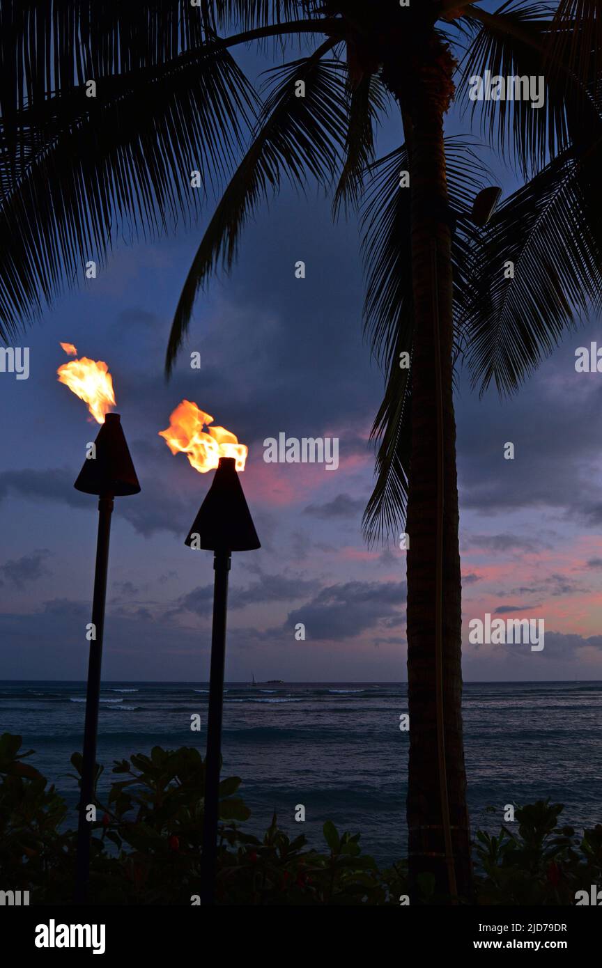 Zwei Fackeln, Teil einer hawaiianischen Kulturtradition, beleuchten einen tropischen Nachthimmel am Waikiki Beach auf Oahu auf Hawaii Stockfoto