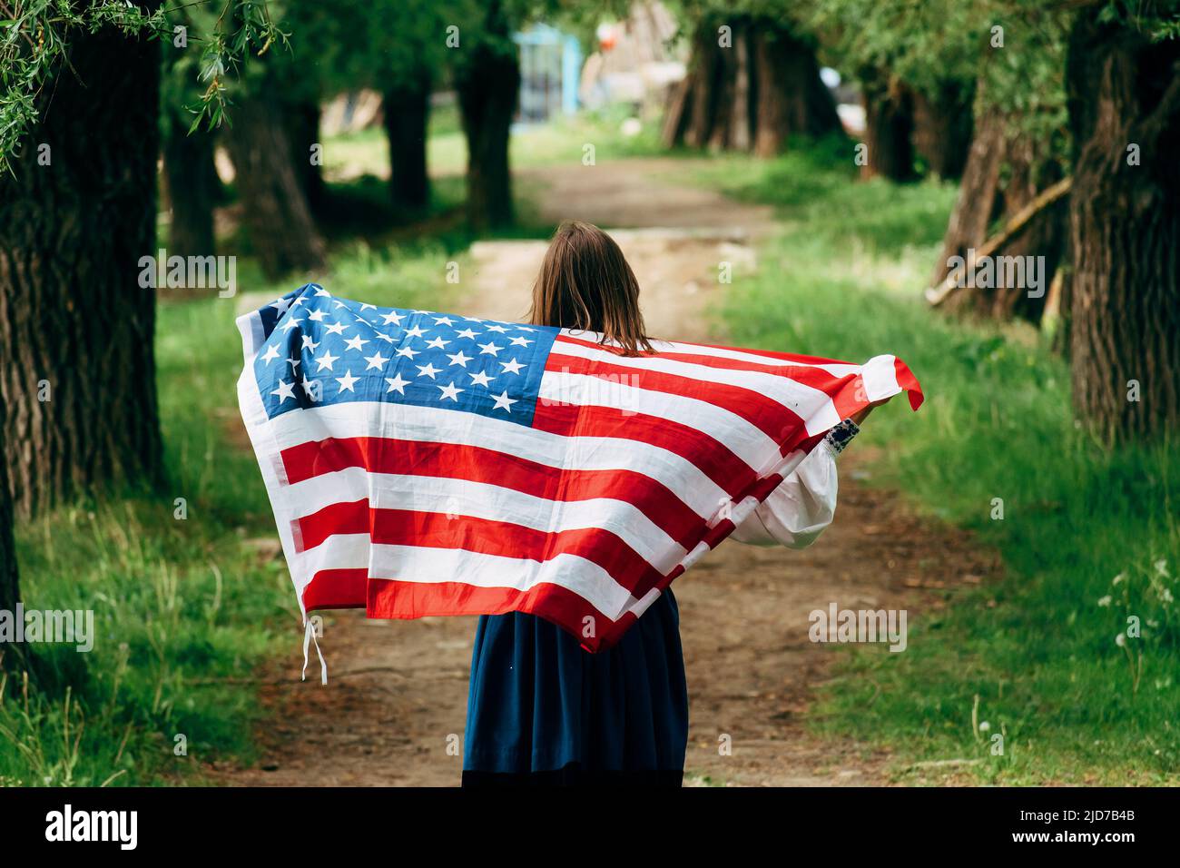 Das Mädchen trägt die amerikanische Flagge. Unabhängigkeitstag der Vereinigten Staaten. Stockfoto