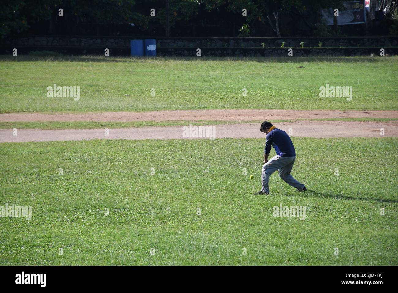 Der junge Mann spielt Cricket im Boden Stockfoto