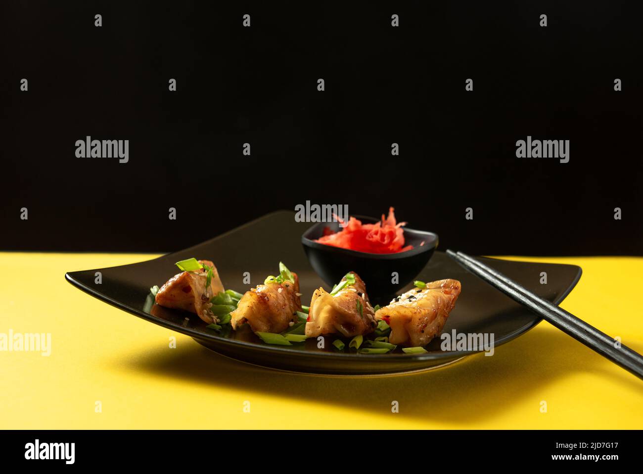 Original japanische Knödel Gyoza mit Huhn und Gemüse. Vorderansicht. Klassische asiatische Küche. Gebratene Gyoza-Knödel auf gelbem Hintergrund Stockfoto