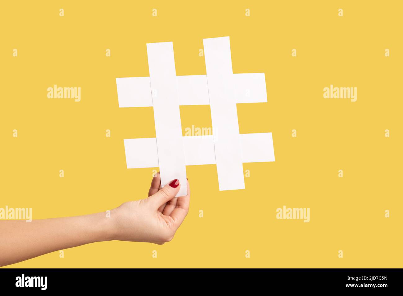 Nahaufnahme einer Frau mit einem großen Hashtag-Symbol aus weißem Papier, Hash-Zeichen für berühmte Medieninhalte, Social Media Marketing und Blog-Werbung. Innenaufnahme des Studios isoliert auf gelbem Hintergrund. Stockfoto