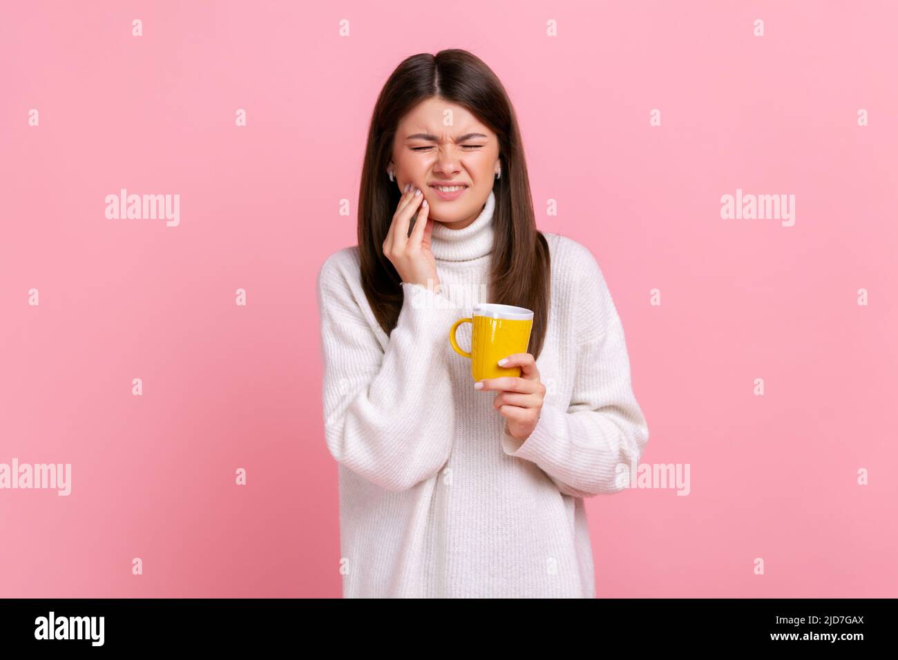 Kranke Brünette Frau leiden unter empfindlichen Zähnen nach dem Trinken heiß oder kalt Getränk, Hohlräume, tragen weißen lässigen Stil Pullover. Innenaufnahme des Studios isoliert auf rosa Hintergrund. Stockfoto