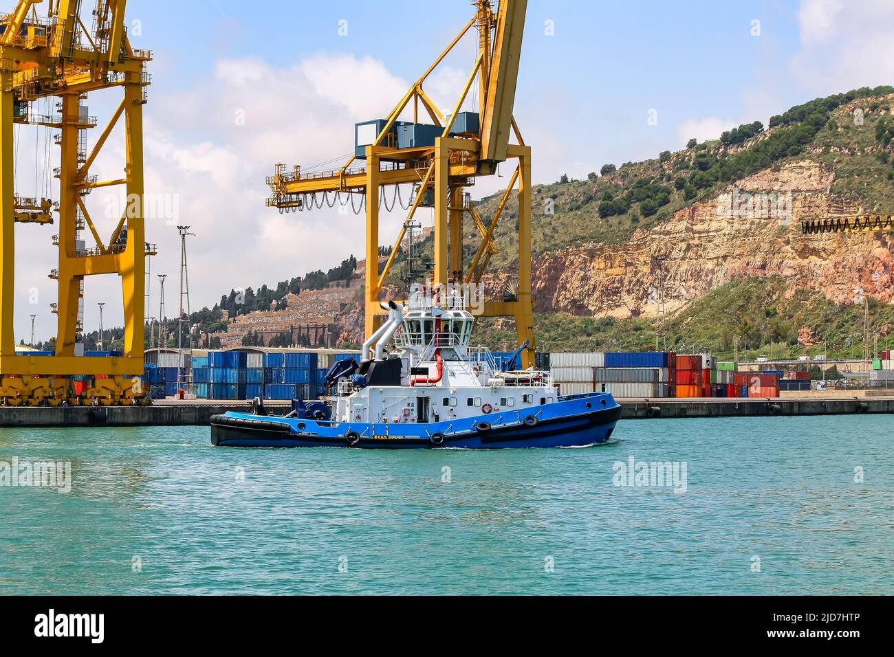 Schlepper im Hafen von Barcelona mit großen Containerkranen. Stockfoto
