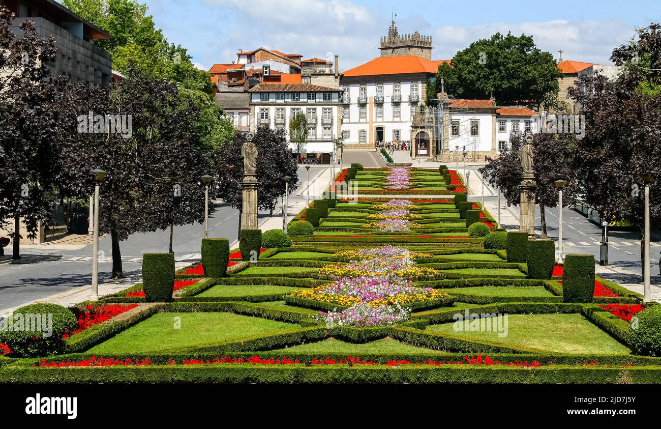 Stadtlandschaft von Guimaraes in Portugal mit seinen symmetrischen Gärten aus grünen Pflanzen und bunten Blumen, Kathedrale und historischen Gebäuden in der Stockfoto