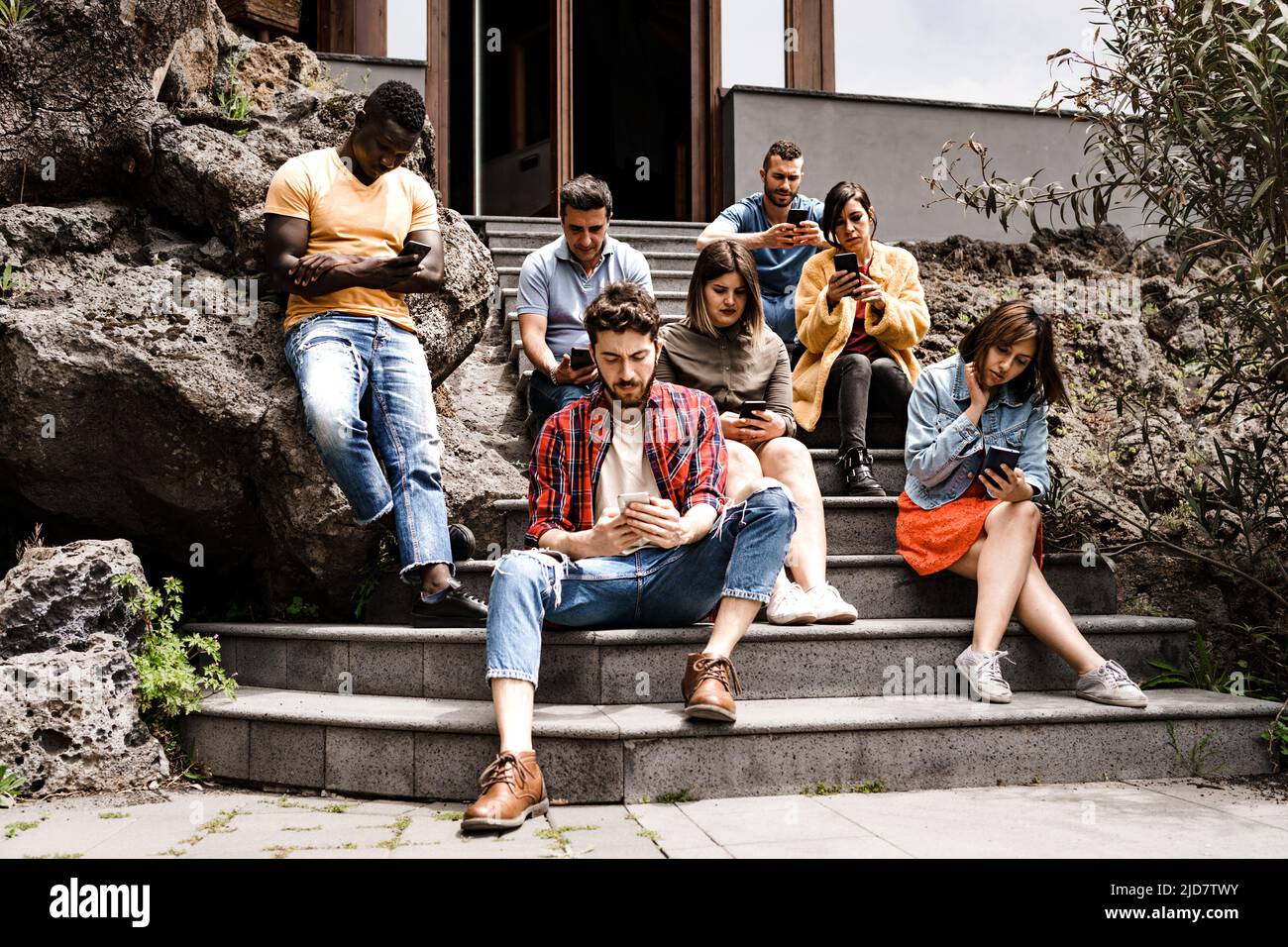 Milenial multiethnischen Freunde Gruppe mit Smartphone sitzen im Treppenhaus Hinterhof - Junge Menschen süchtig nach Handy - Menschen Phubbing und Stockfoto