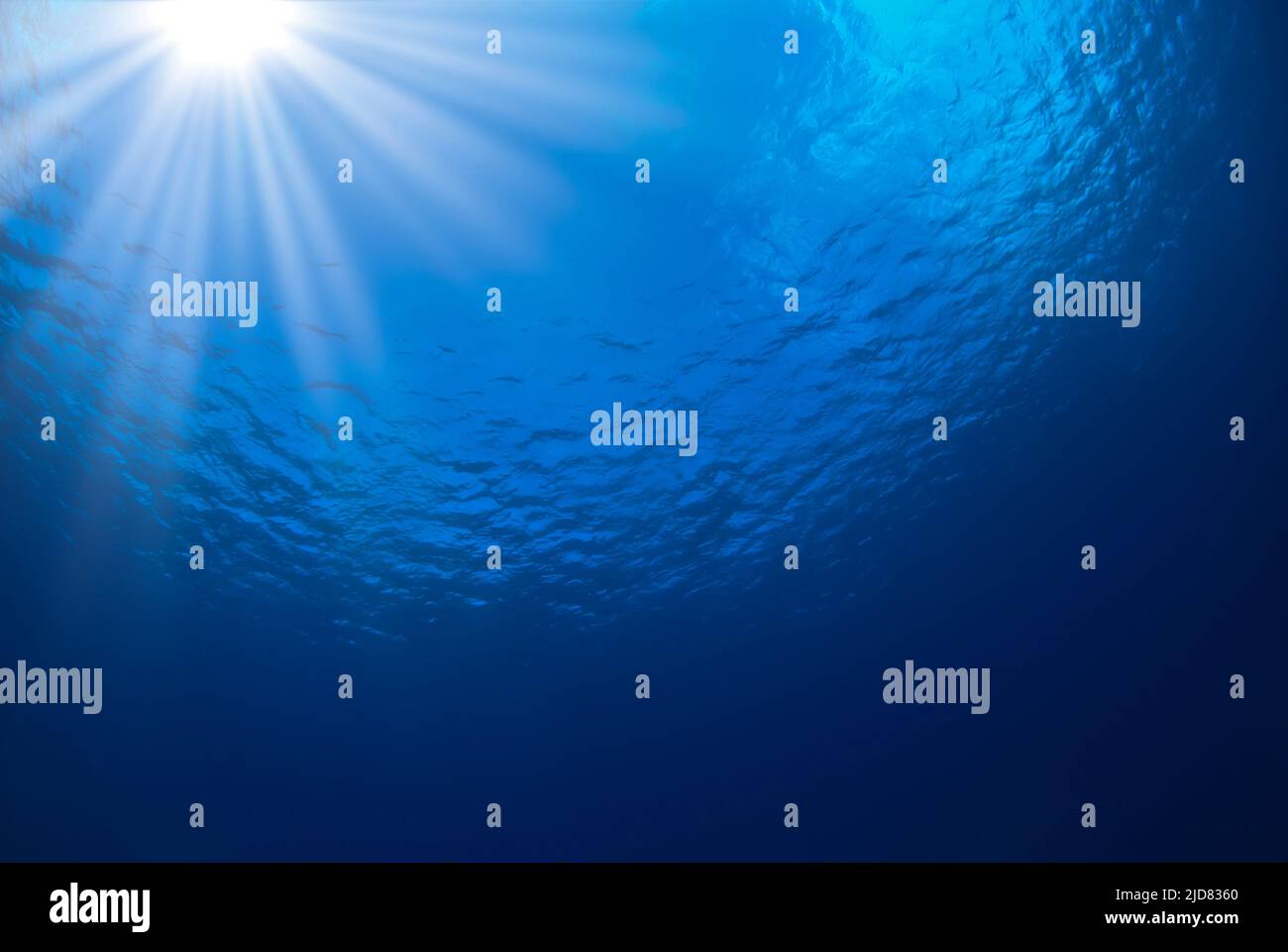 Ozeanblauer Hintergrund mit Sonnenstrahlen in der linken oberen Ecke Stockfoto