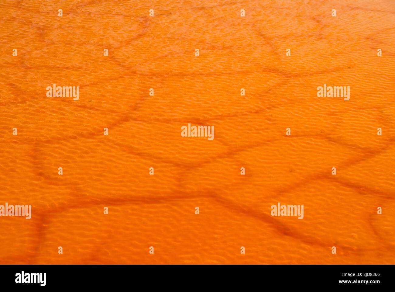 Strukturierter, rissiger Schlamm, der von geriffeltem Orangenwasser bedeckt ist Stockfoto
