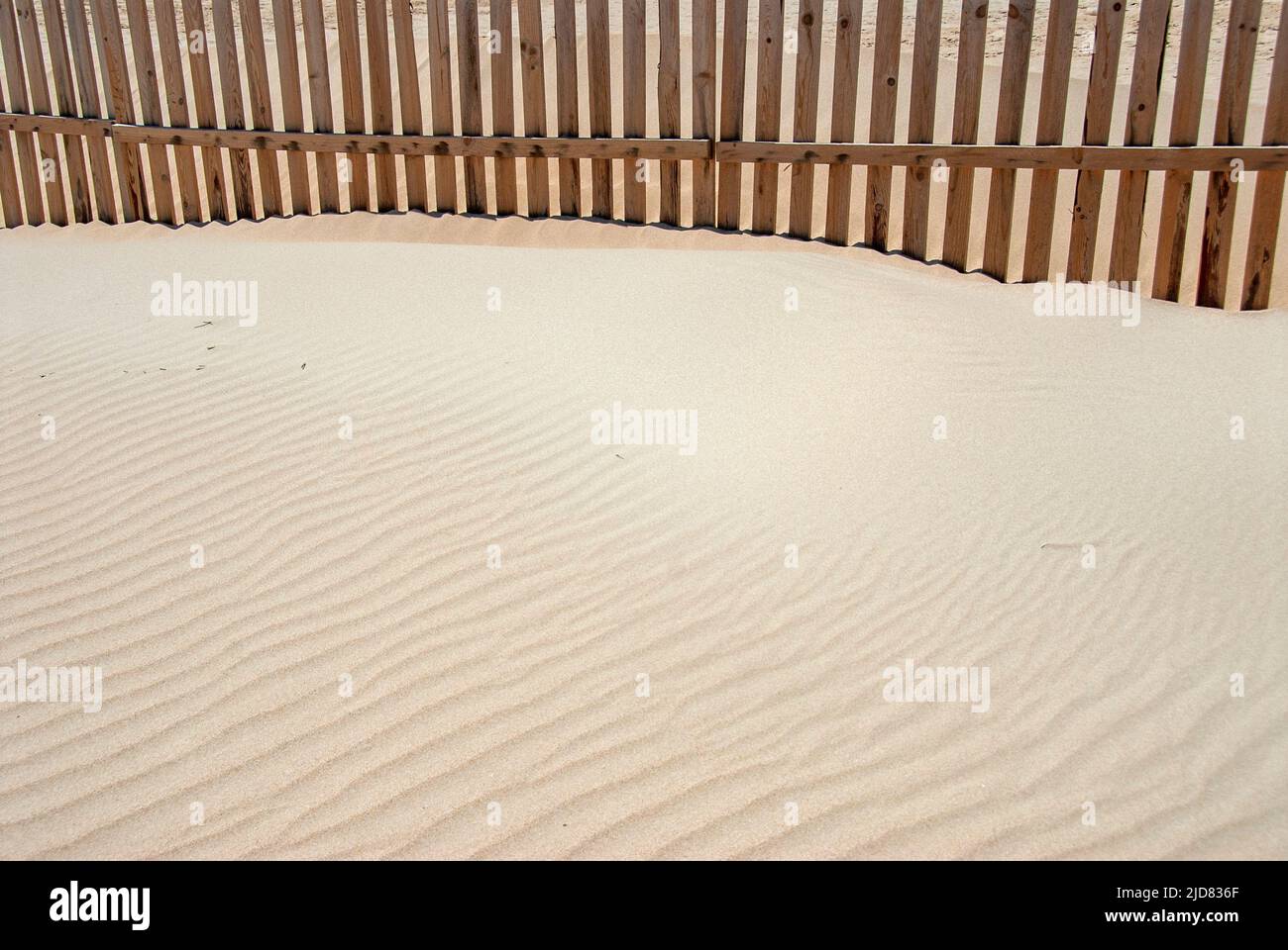 Textur eines gewellten Sandes mit einem Zaun in der Spitze Stockfoto