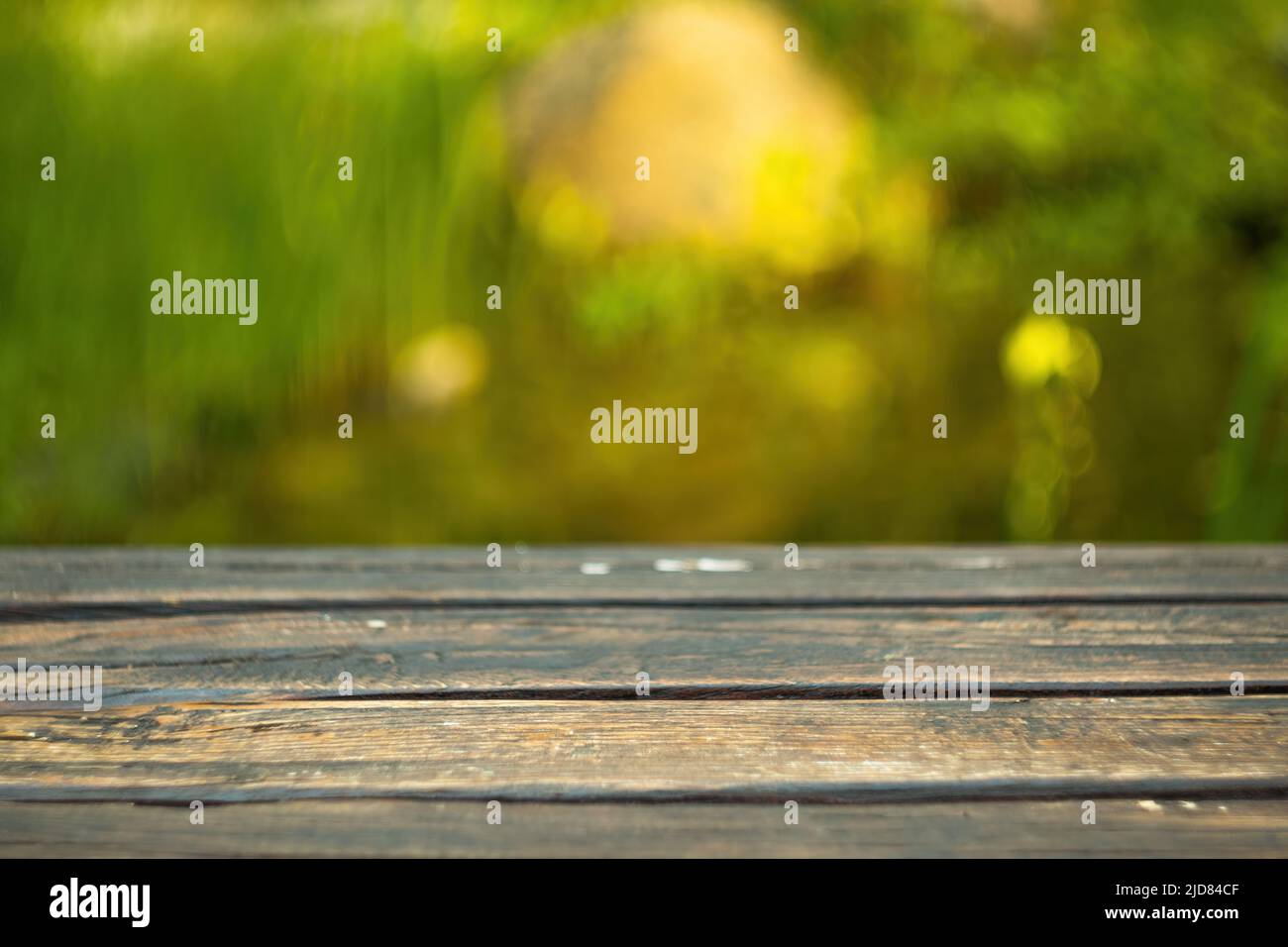 Verschwommener Hintergrund des grünen Parks im Sommer, Holz Tischplatte auf glänzendem Bokeh grünen Hintergrund. Für die Produktanzeige Stockfoto