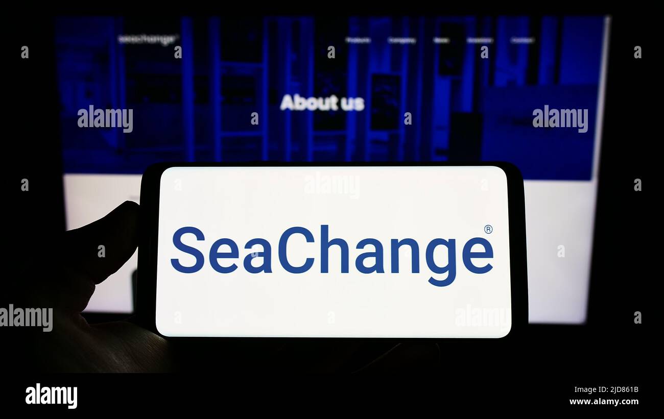Person, die das Smartphone mit dem Logo des US-Unternehmens SeaChange International Inc. Auf dem Bildschirm vor der Website hält. Konzentrieren Sie sich auf die Telefonanzeige. Stockfoto