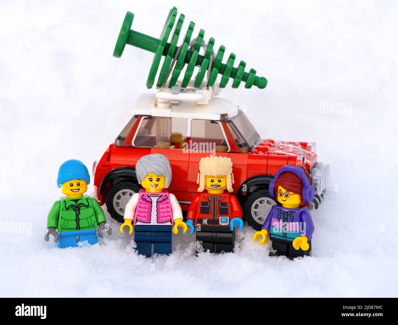 Tambow, Russische Föderation - 19. Januar 2022 Familie Lego steht vor einem roten Auto, das einen Weihnachtsbaum hat und im Schnee steht. Stockfoto