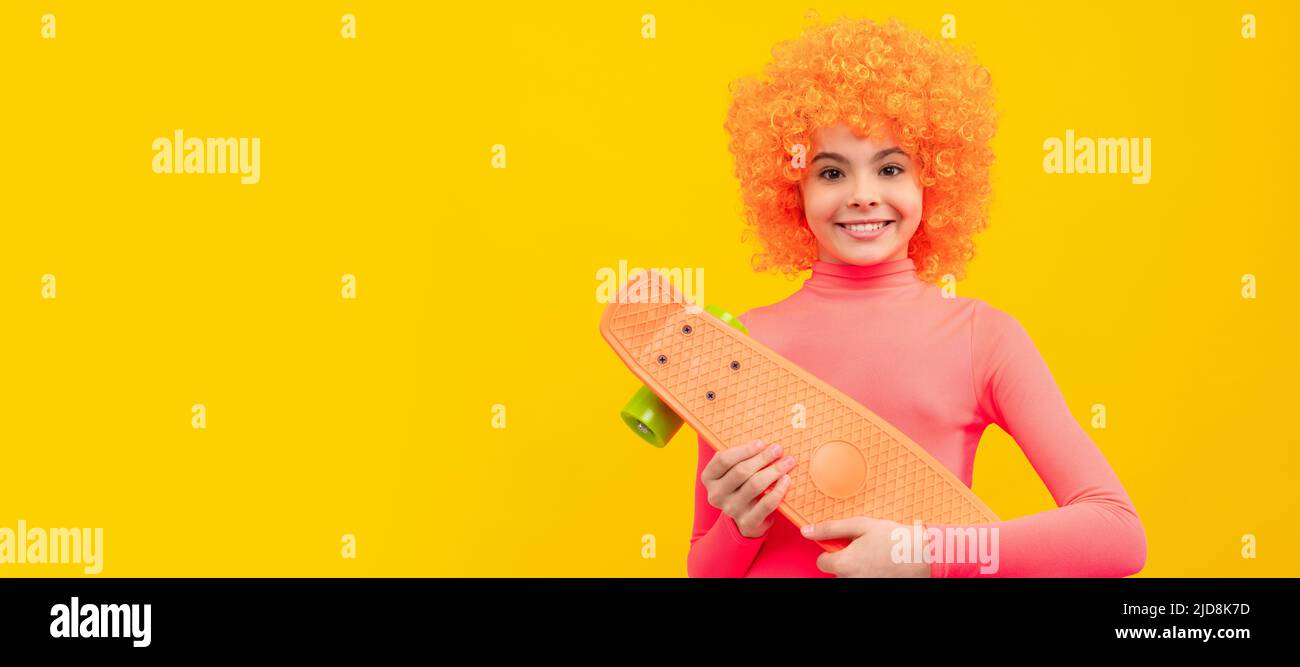 Happy Girl Scater mit orangen Haaren in rosa Poloneck Lächeln hält Pennyboard, Skateboarding. Lustige Teenager Kind auf der Party, Poster Banner Header mit Stockfoto