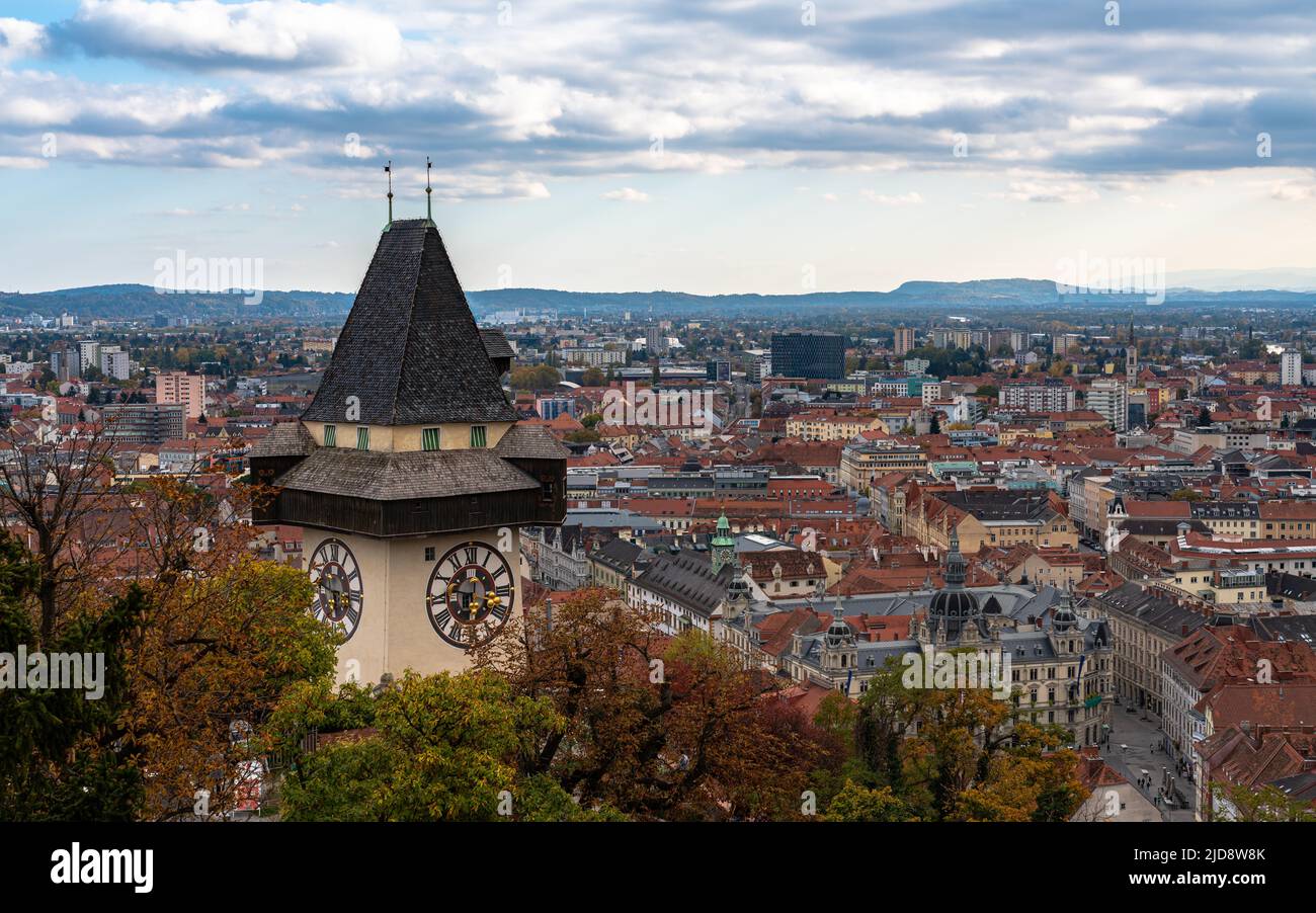 Luftpanorama der Grazer Altstadt vom Schlossberg mit Uhrturm und Rathaus am Herbsttag, mit blauer Himmelswolke und bunten Bäumen, Gras Stockfoto