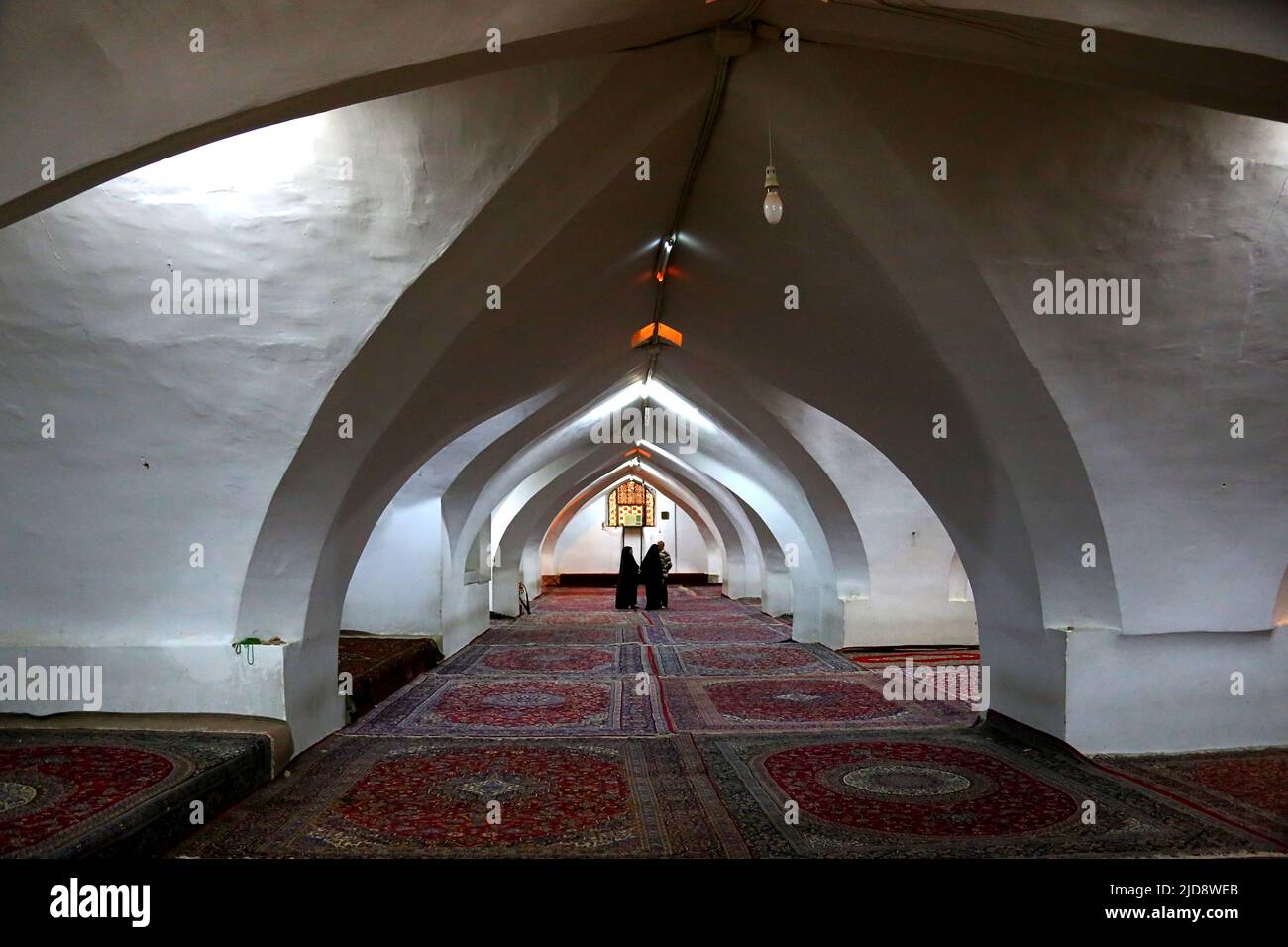 Gebetssaal für Frauen in der Freitsmoschee in Isfahan, Iran. Im Hintergrund sind zwei verhüllte Frauen sichtbar. The Boden is vollstndig with teppichen ausgelegt. Stockfoto