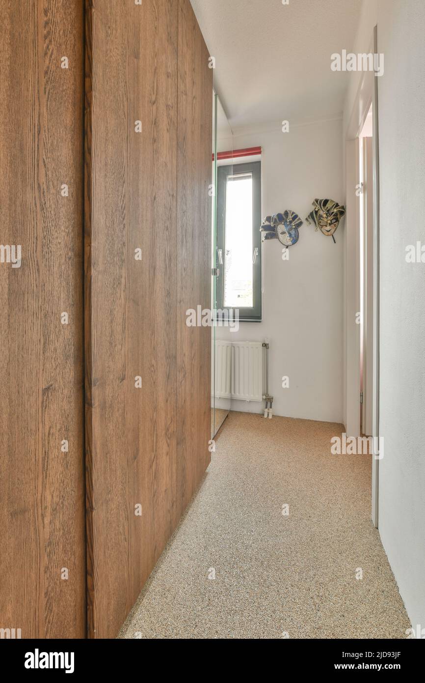 Ein kompakter, heller Korridor mit weißen Wänden und Fliesenboden Stockfoto