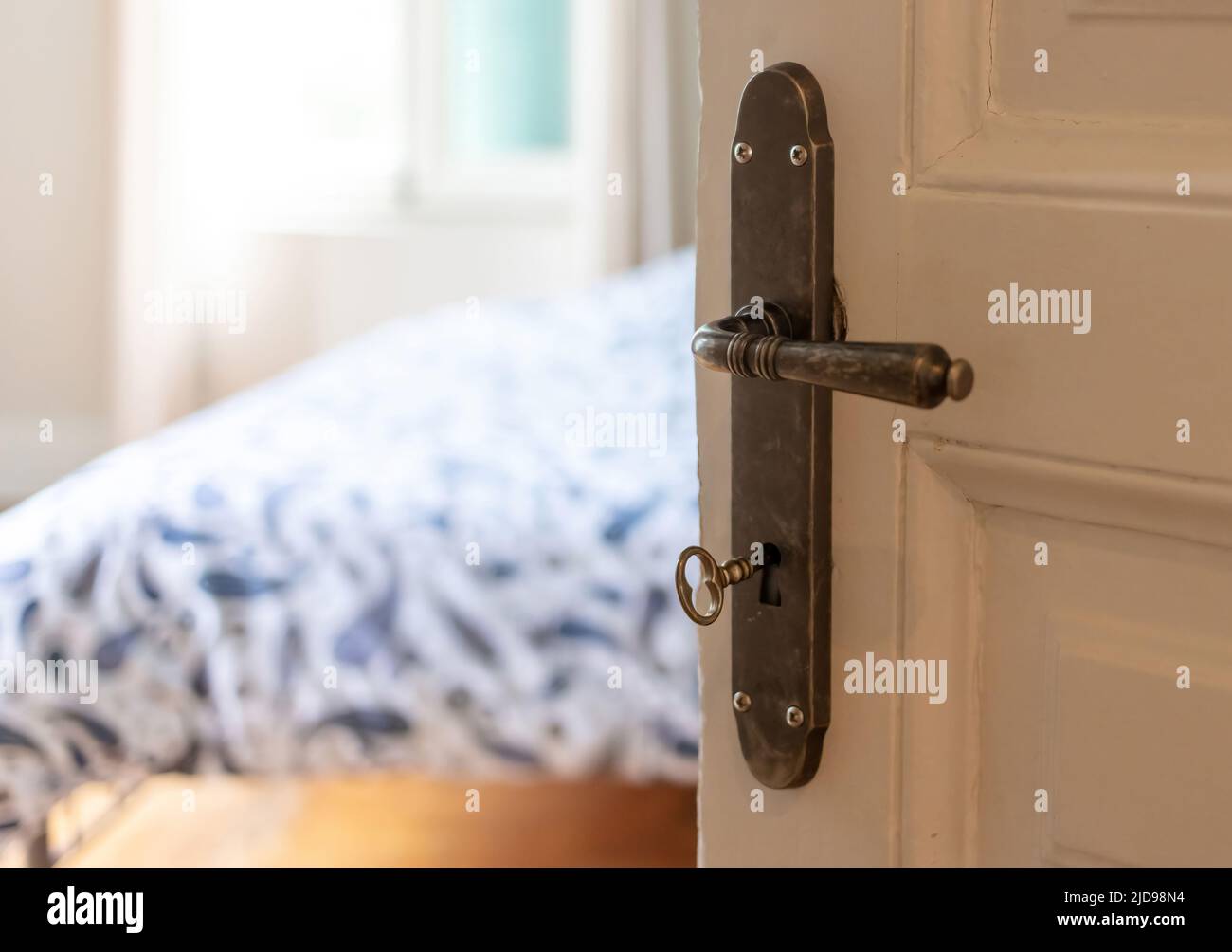 Stilvolle Einrichtung eines Hotelzimmers oder eines Hauszimmers. Tür offen, Retro-Türknopf und Schlüssel an weißer Vintage-Holztür, Nahaufnahme. Stockfoto