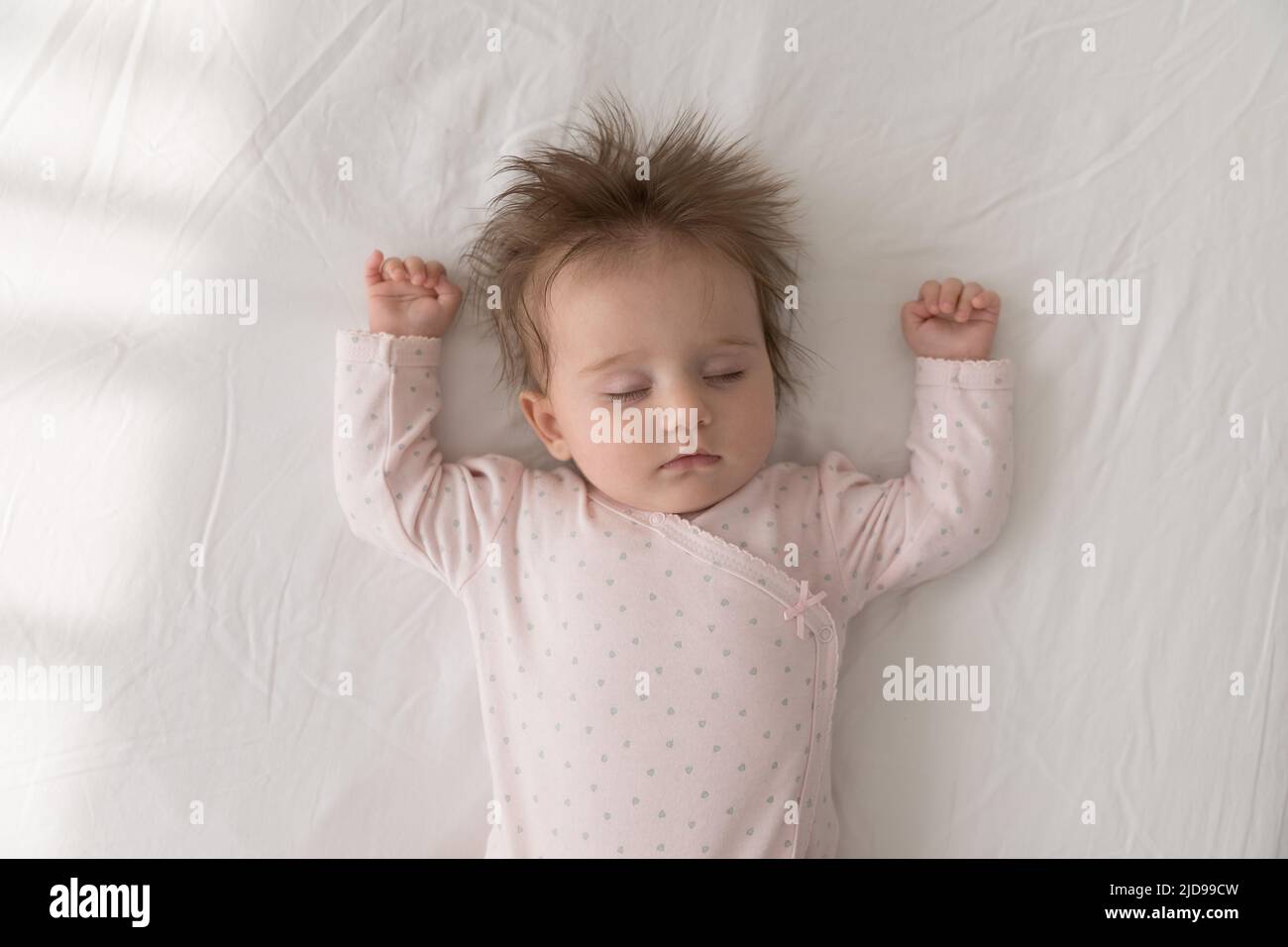 Niedliches Baby, das alleine auf dem Bett schläft, über der Aussicht Stockfoto