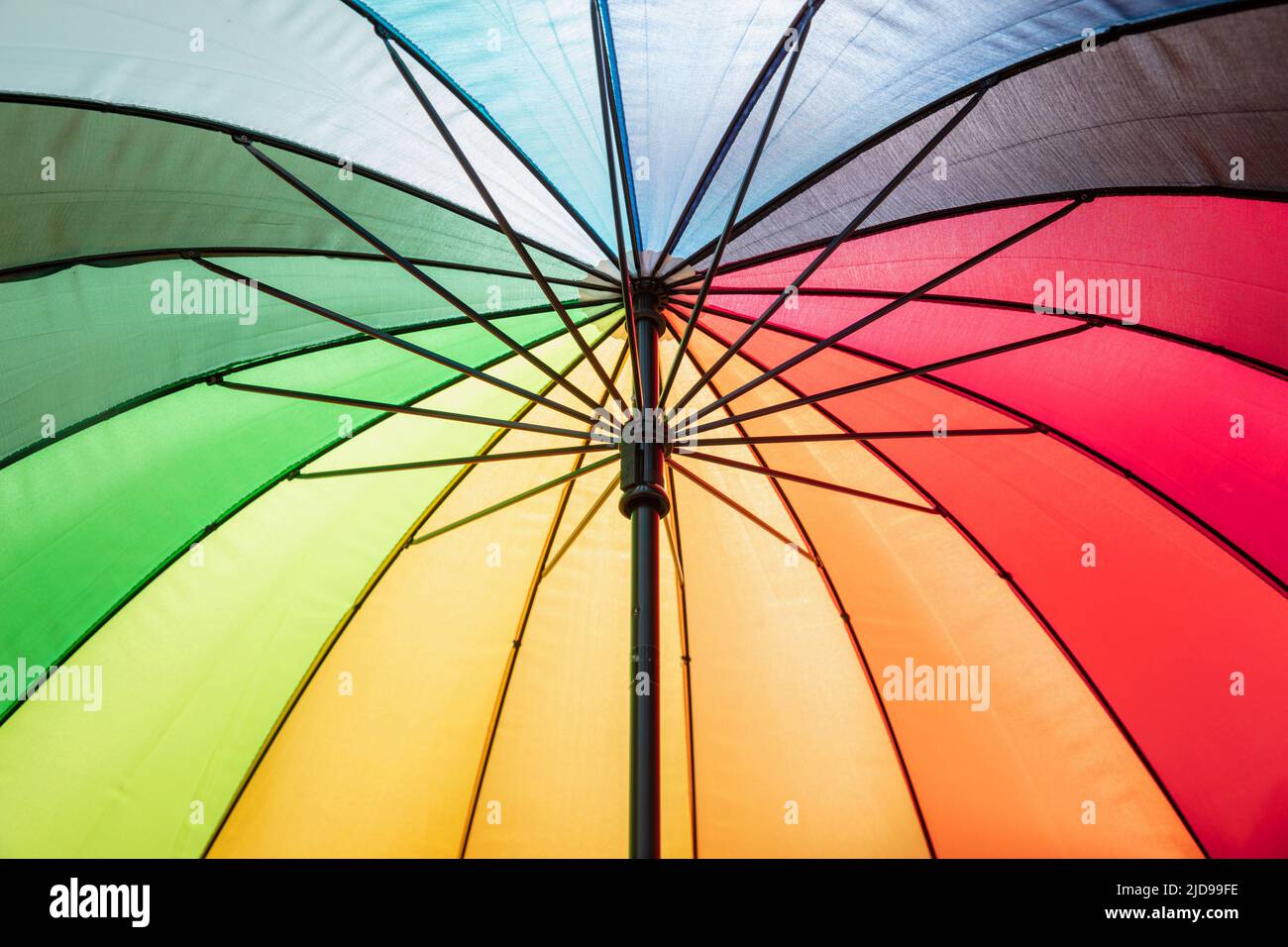 Regenbogenfarbe Regenschirm Hintergrund. Mehrfarbige Farbspektrumfarben Sonnenschutz, offener, sonniger Tag, Sonnenschutz Stockfoto