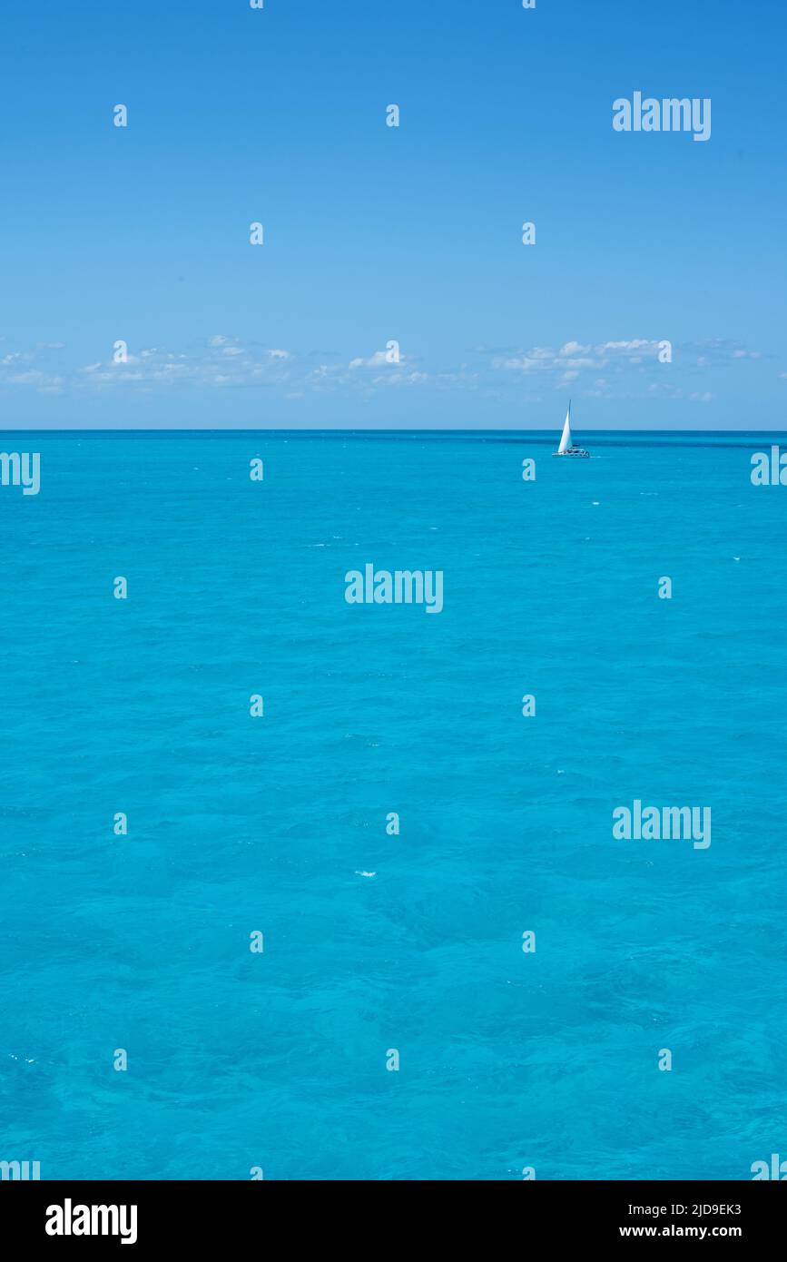 Ein Segelboot am Horizont im kristallklaren tropischen Meer vor dem blauen Himmel eines Sommertages. Reiseurlaub Stockfoto