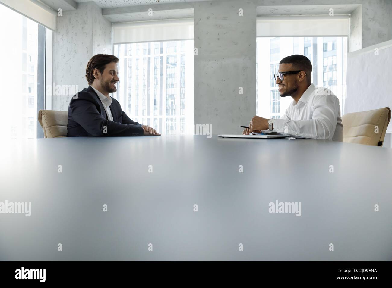 Während der formellen Besprechung sitzen multiethnische Geschäftsleute am Schreibtisch im Sitzungssaal Stockfoto