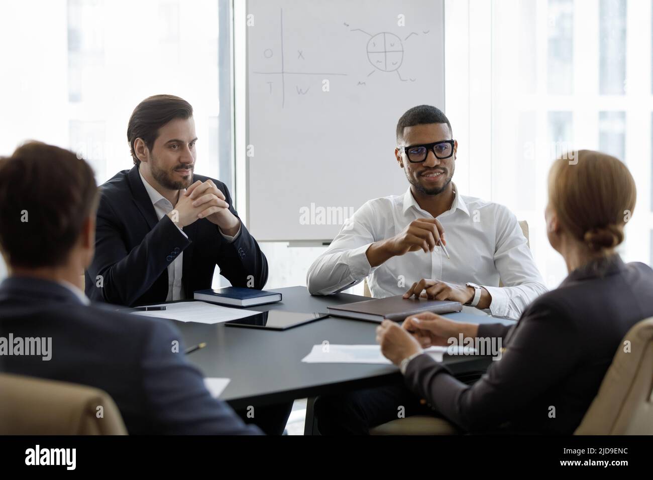Multinationale Geschäftsleute nehmen an der formellen Gruppentreffen im Sitzungssaal Teil Stockfoto