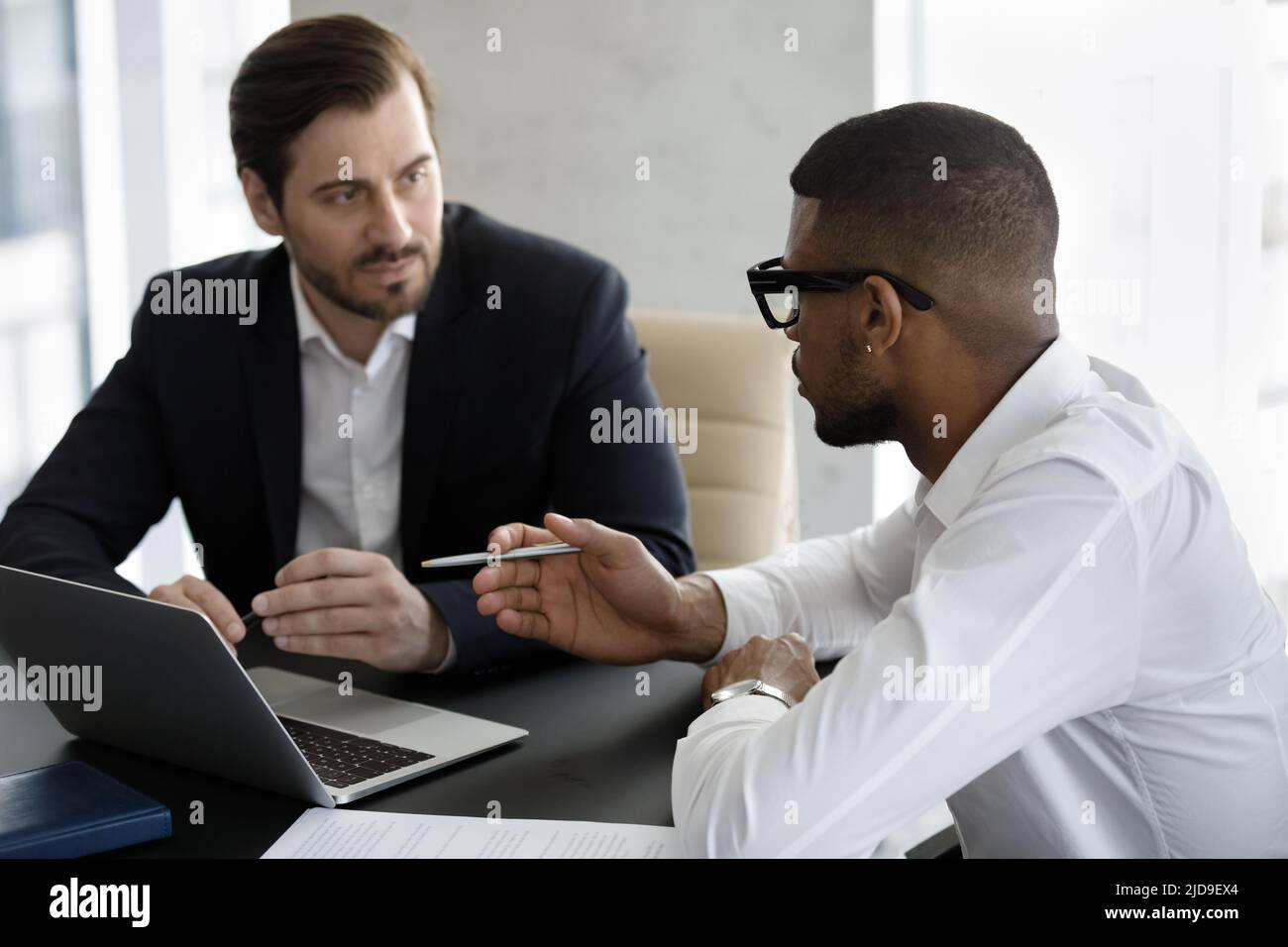 Zwei verschiedene Geschäftsleute, die während des Meetings in einem modernen Büro verhandeln Stockfoto