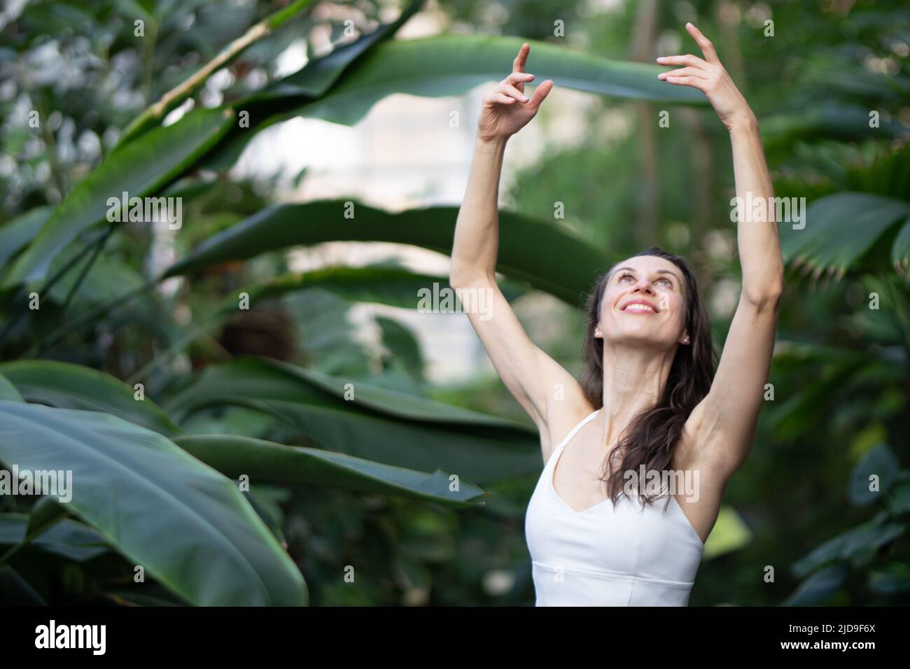 Frauen meditieren und praktizieren Yoga im tropischen Regenwald. Schöne junge Frau praktiziert Yoga im Freien mit tropischen Wald im Hintergrund. Stockfoto