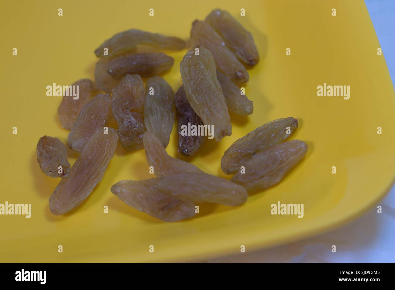 Rosinen oder getrocknete Trauben auf einer gelben Oberfläche Stockfoto