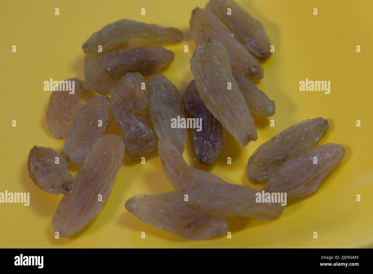 Rosinen oder getrocknete Trauben auf einer gelben Oberfläche Stockfoto