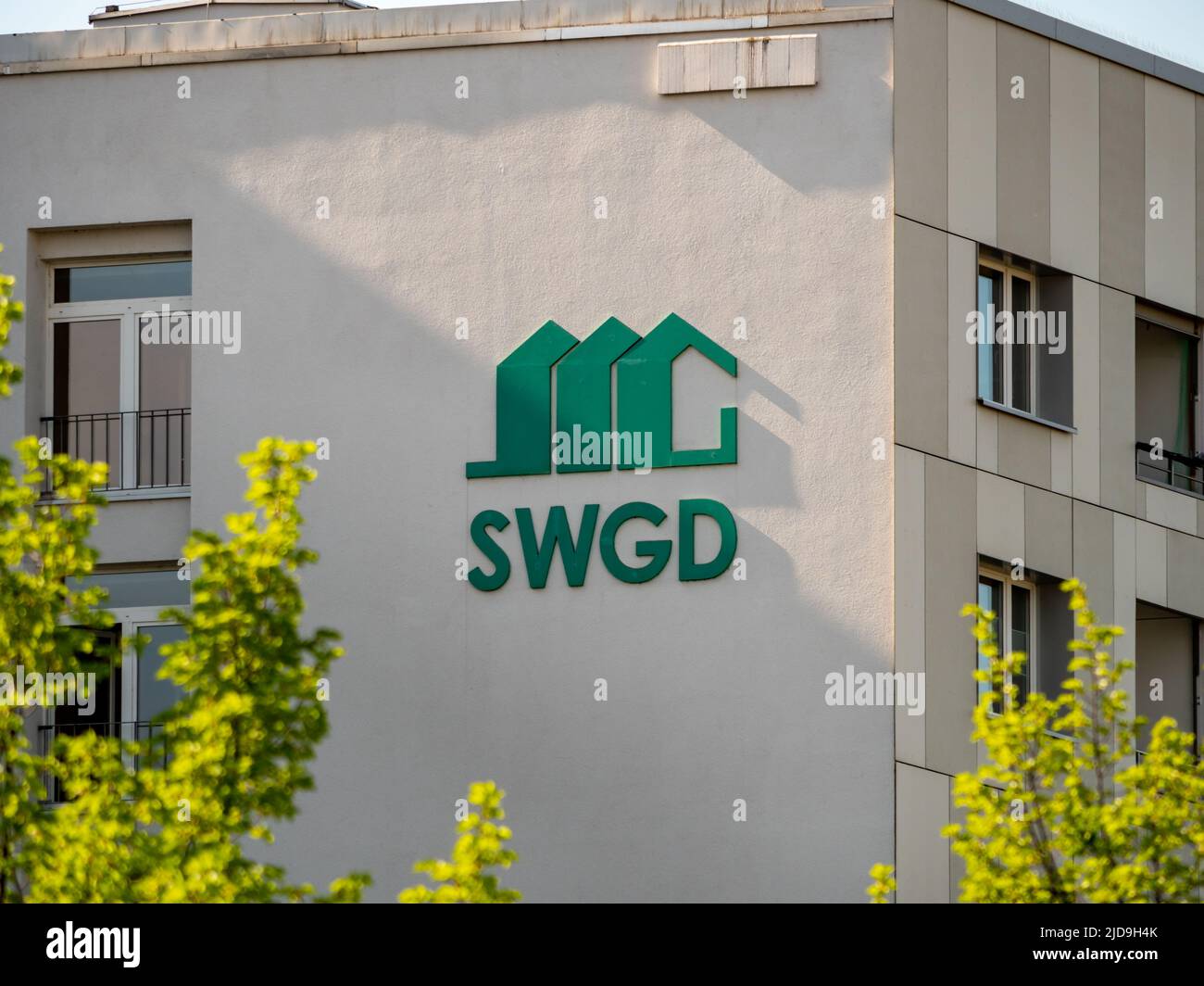 SWGD-Logo und ein Außengebäude in der Stadt. Die Sächsische Wohnungsgenossenschaft Dresden unterzeichnet. Stockfoto